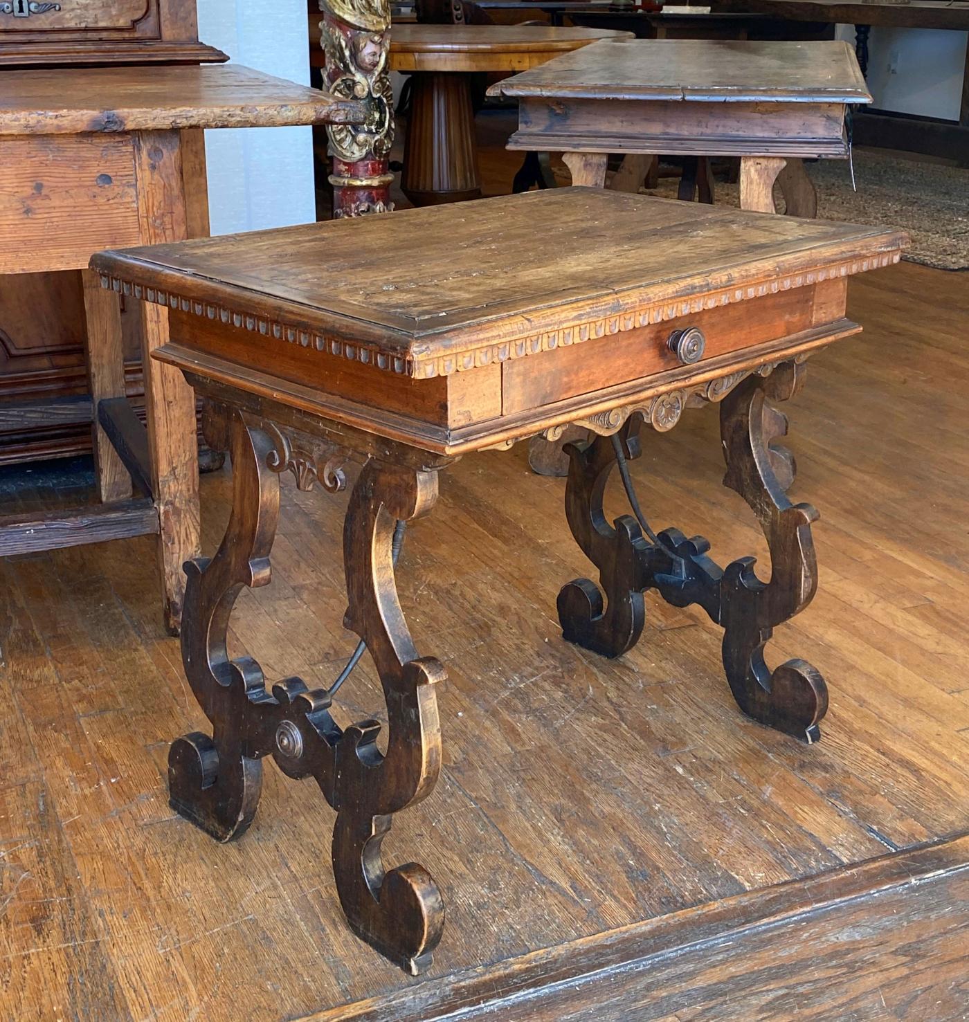Il piano rettangolare con bordo modanato sopra un fregio scanalato e sollevato su supporti a cavalletto sagomati con piedini sottosquadro uniti da barelle in ferro ad arco. 