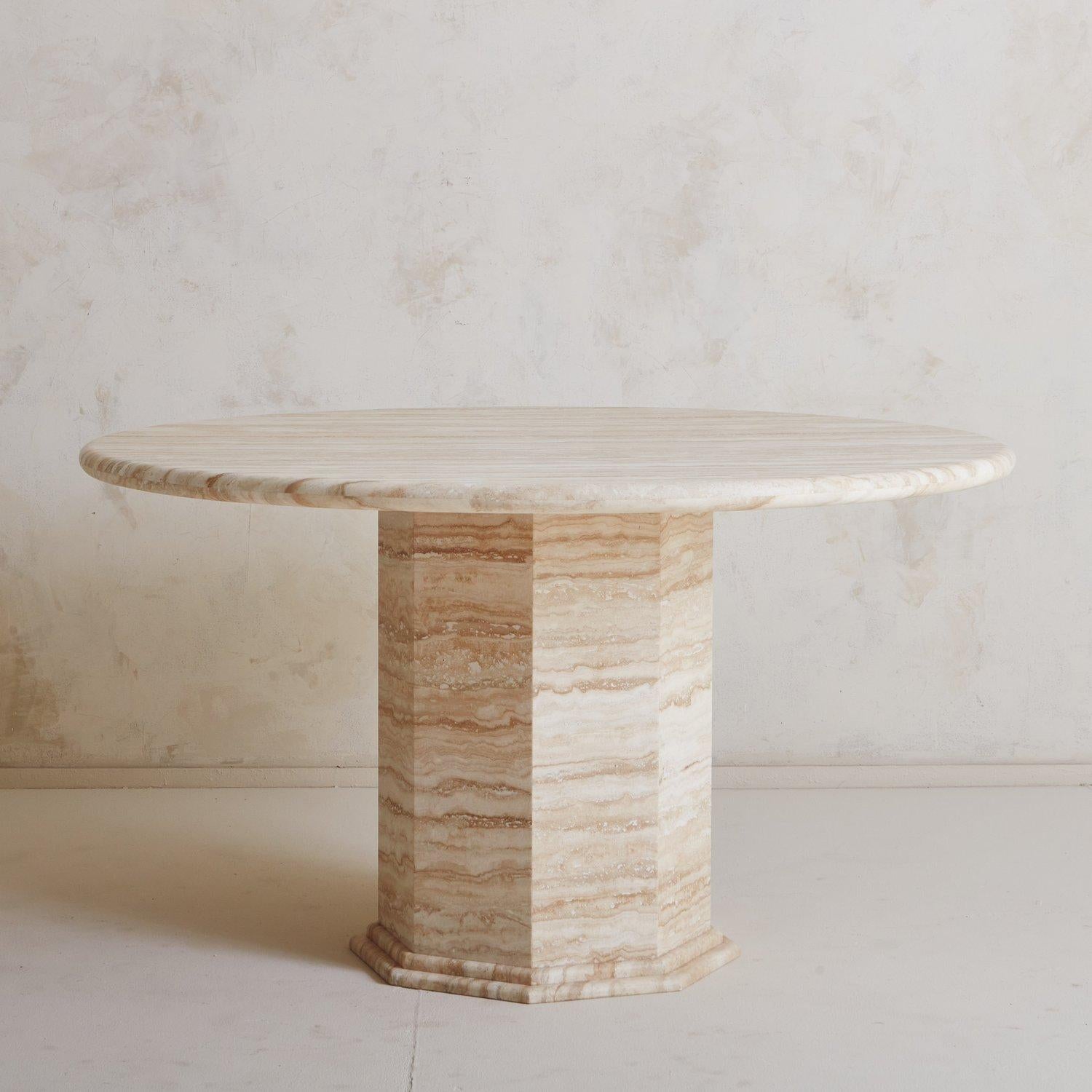 A stunning custom travertine dining table designed in house by South Loop Loft. This table features a round top resting on an octagonal mitered edge base with a double banded-edge detail.

This table is available on a Made to Order Basis. It is