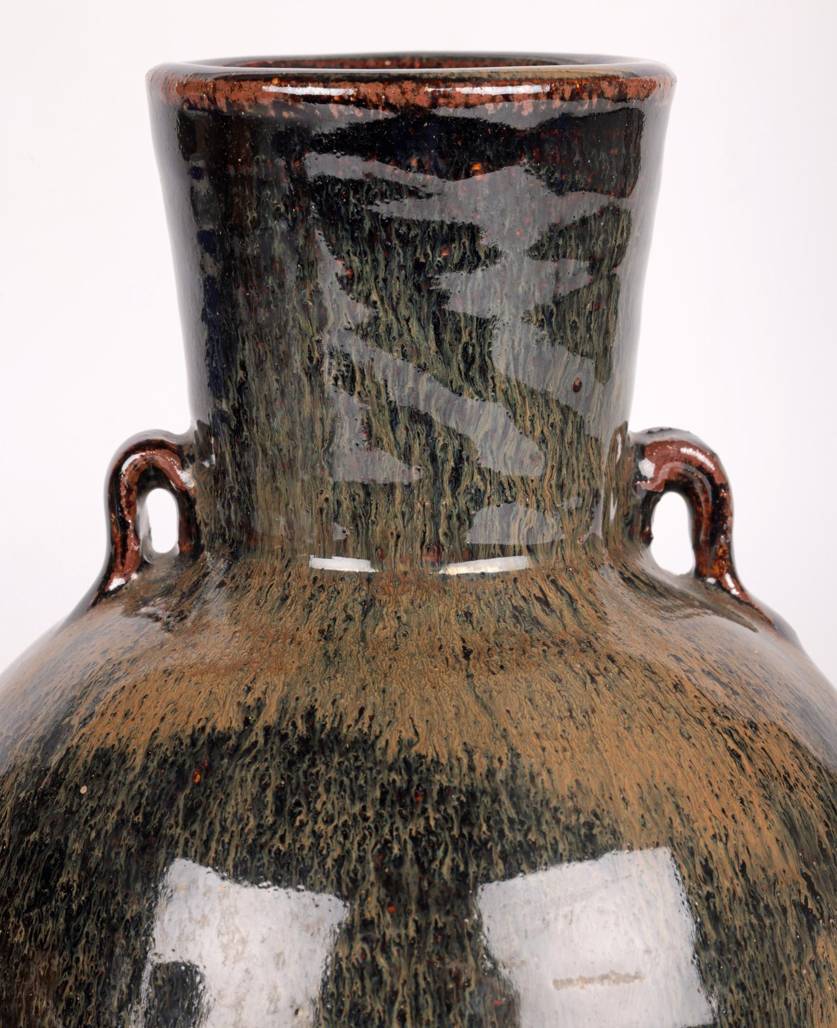 A stylish Leach Pottery, St Ives hand thrown twin handled studio pottery vase decorated in haresfur effect glazes by renowned potter Trevor Corser (British, 1938-2015) and dating from the 1970’s. The heavily potted vase of flagon shape stands on a