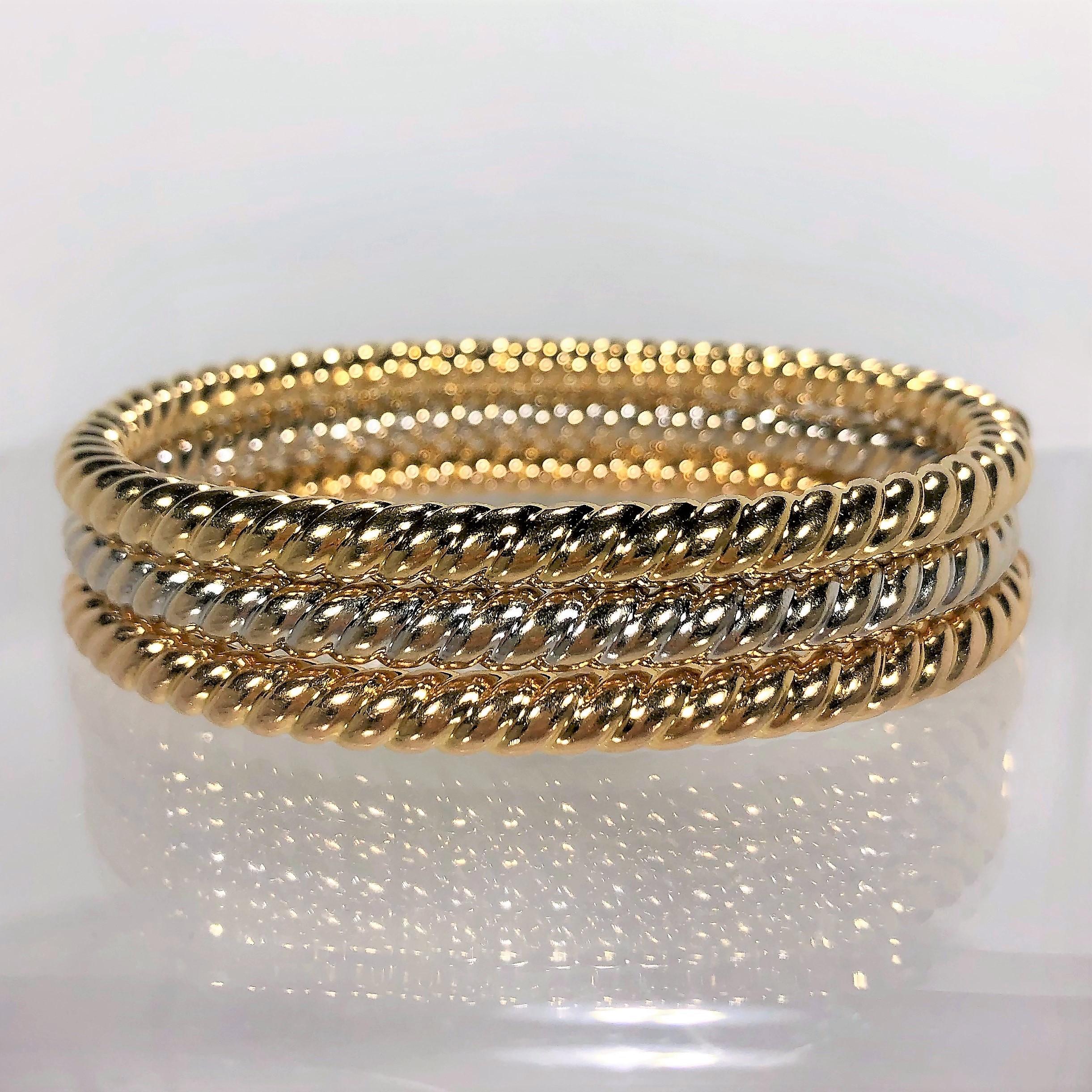 Set of three Italian, twisted rope, oval shaped bangles. One in 18K Yellow Gold, one in 18K White Gold and one
in 18K Rose Gold. When worn together the three are 9/16 inch wide total. Hinged on one side. 6 7/8 inch inside circumference. Fits a