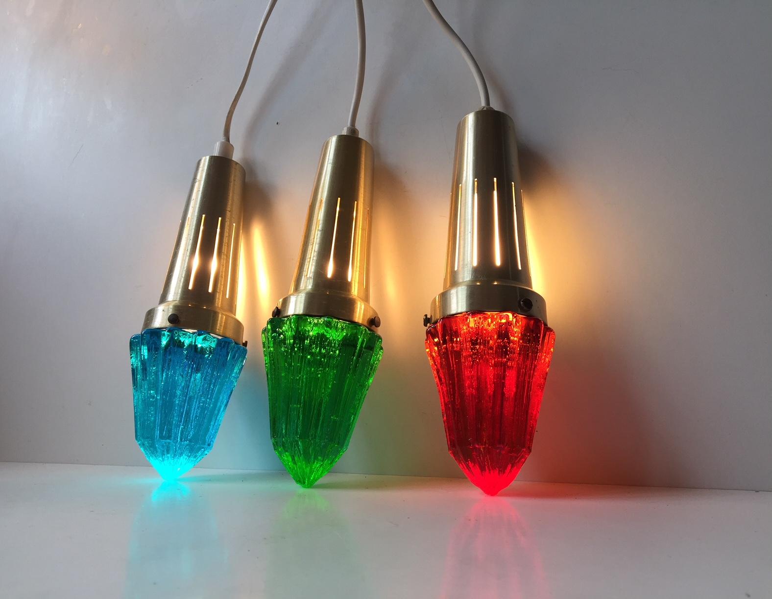 Ce trio de lampes suspendues en forme de glaçon est fabriqué en verre épais texturé et coloré et en aluminium anodisé au laiton. L'ensemble a été fabriqué et conçu par Vitrika au Danemark dans les années 1960. Les abat-jour en verre ont été