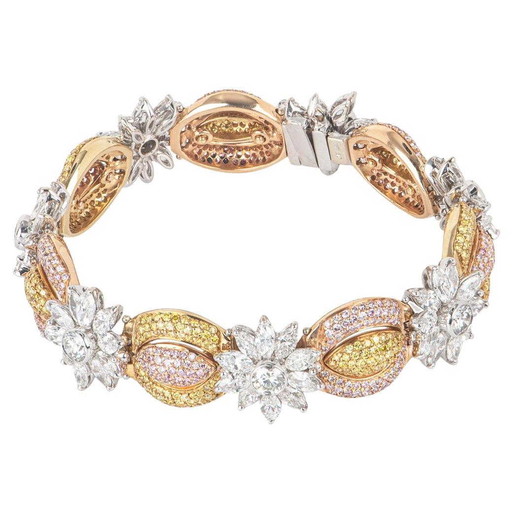 An exquisite 18k tri-colour gold fancy diamond bracelet. The bracelet is set with a pleasing mix of white, fancy intense yellow and natural pink diamonds. The 7 round brilliant cut diamonds, set in white gold, have an approximate total weight of