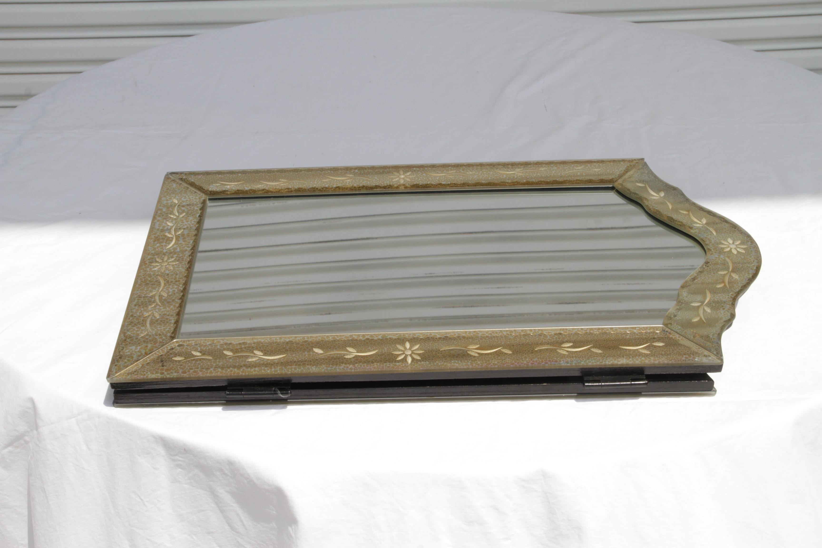 Triptych vanity mirror featuring beveled, mirrored borders around each mirror panel proper. Piece is embellished on borders with gilt foliage and linear accents.