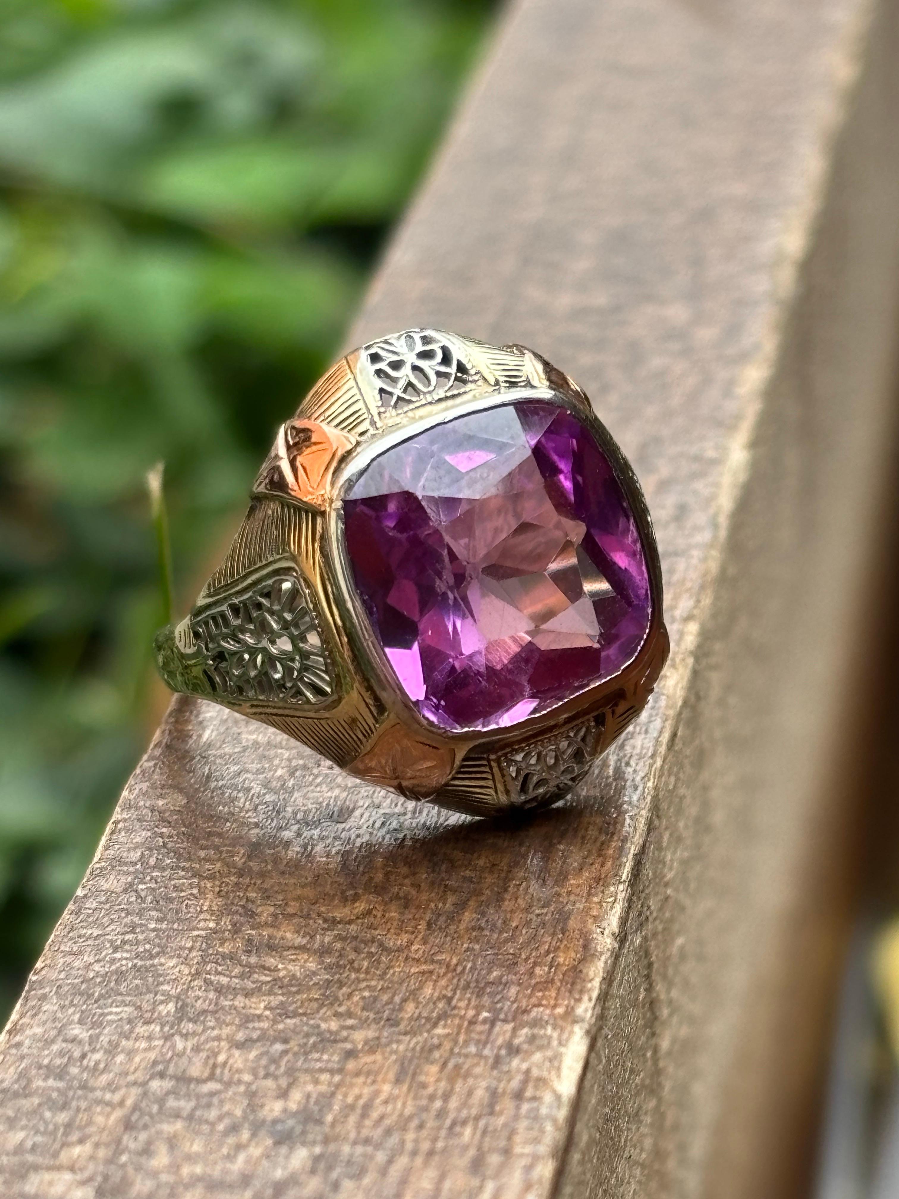 This striking 1980’s tri-tone gold filigree ring is a bold statement of vintage artistry, showcasing a vibrant cushion-cut synthetic amethyst weighing approximately 4.50 carats. Crafted in 14k yellow, rose, and white gold, the ring highlights the