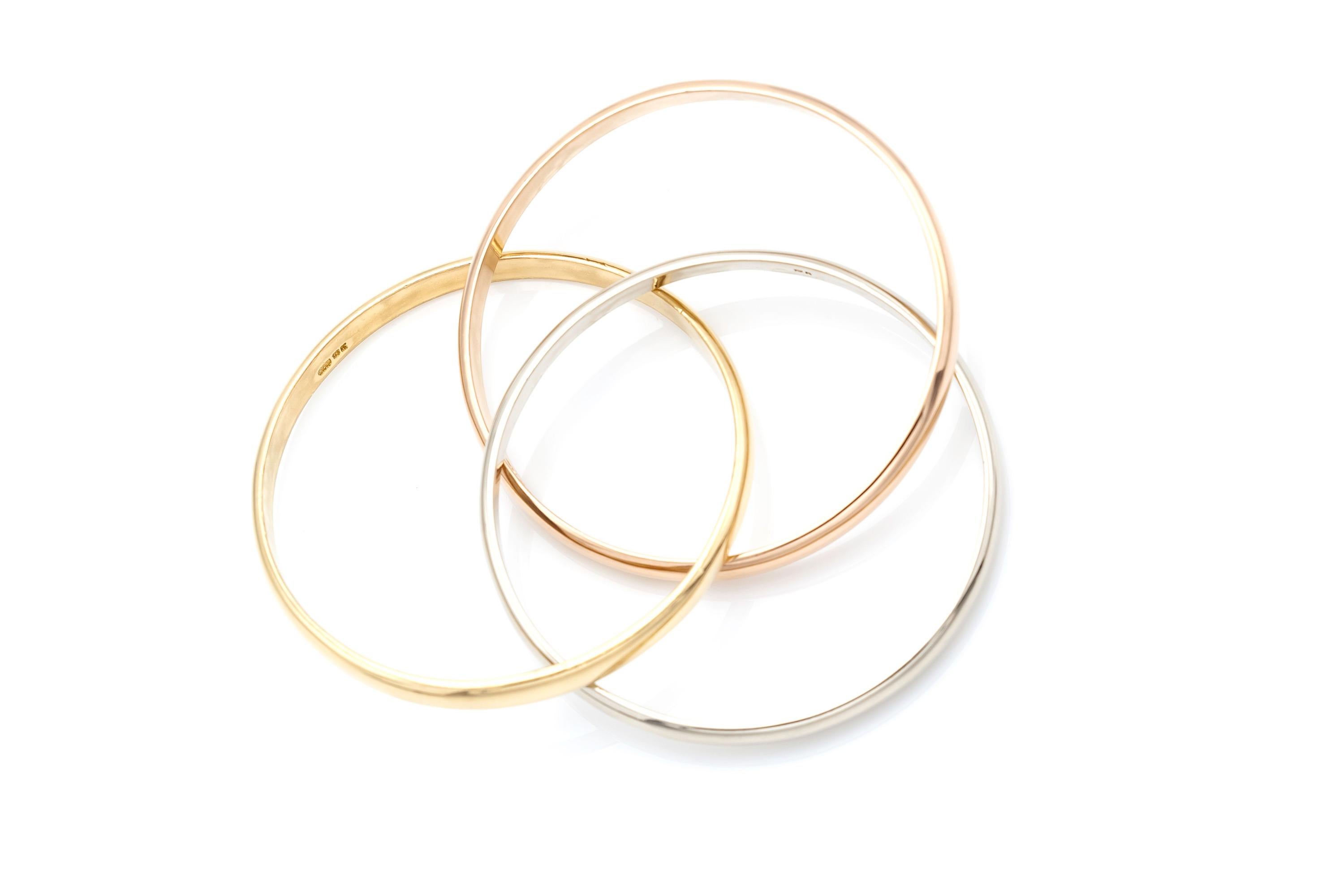 Three interconnected bangles finely crafted in 18K yellow, white, and rose gold.