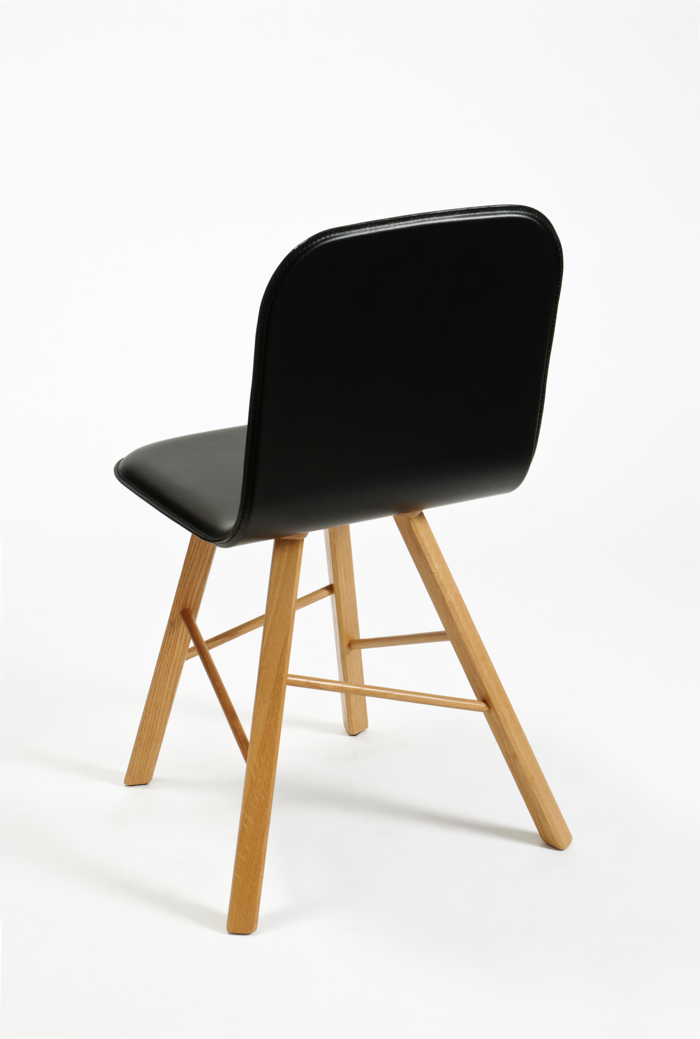 Essentieller und eleganter Stuhl mit einer gebogenen Sperrholzschale und vier ikonischen Beinen mit dreieckiger Form aus massiver Eiche, die durch quer verlaufende Holzstangen verbunden sind.
Die Schale ist mit Naturleder gepolstert, das auch in