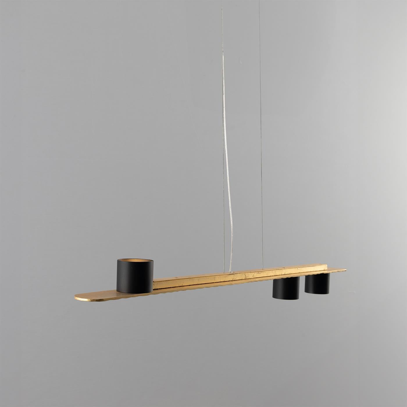 Síntesis fascinante entre elegancia contemporánea y calidad artesanal, esta lámpara de araña sorprende por su refinado diseño lineal. Minuciosamente martilleada, la barra de metal estructural luce un acabado dorado espléndidamente realzado por el