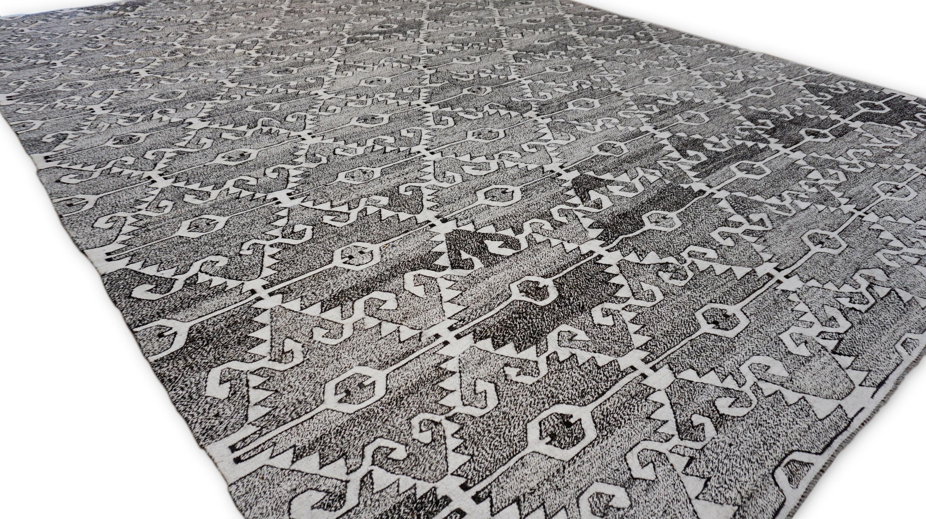 Dieser handgewebte Wollteppich zeigt ein auffälliges geometrisches Stammesmuster, das von traditionellen Kelim-Motiven inspiriert ist. Der von geschickten Kunsthandwerkern gefertigte Teppich zeigt ein kompliziertes Allover-Muster aus sich