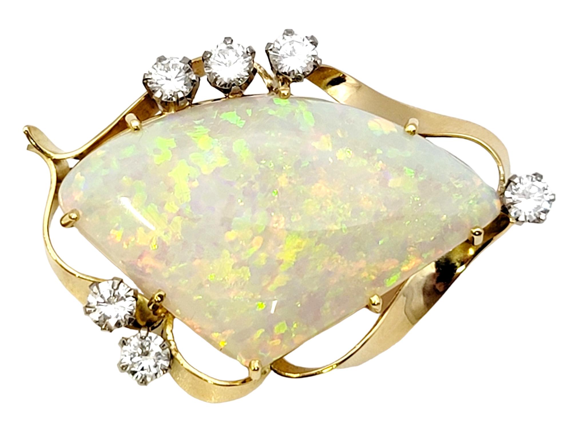 This exquisite opal and diamond brooch absolutely glows. The radiant cabochon opal stone has an incredible play of color, shimmering from every angle with its iridescent beauty. The stone is prong set in polished yellow gold and arranged in a
