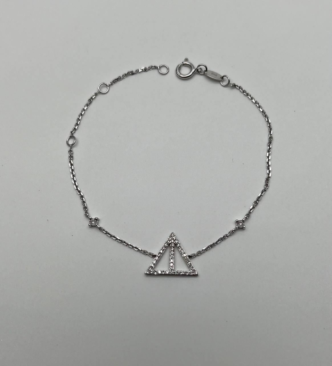 Ce délicat bracelet présente une fine chaîne en or blanc ornée d'un pendentif triangulaire géométrique incrusté de pierres étincelantes. Le design minimaliste est rehaussé par de petits diamants régulièrement espacés le long de la chaîne. En or