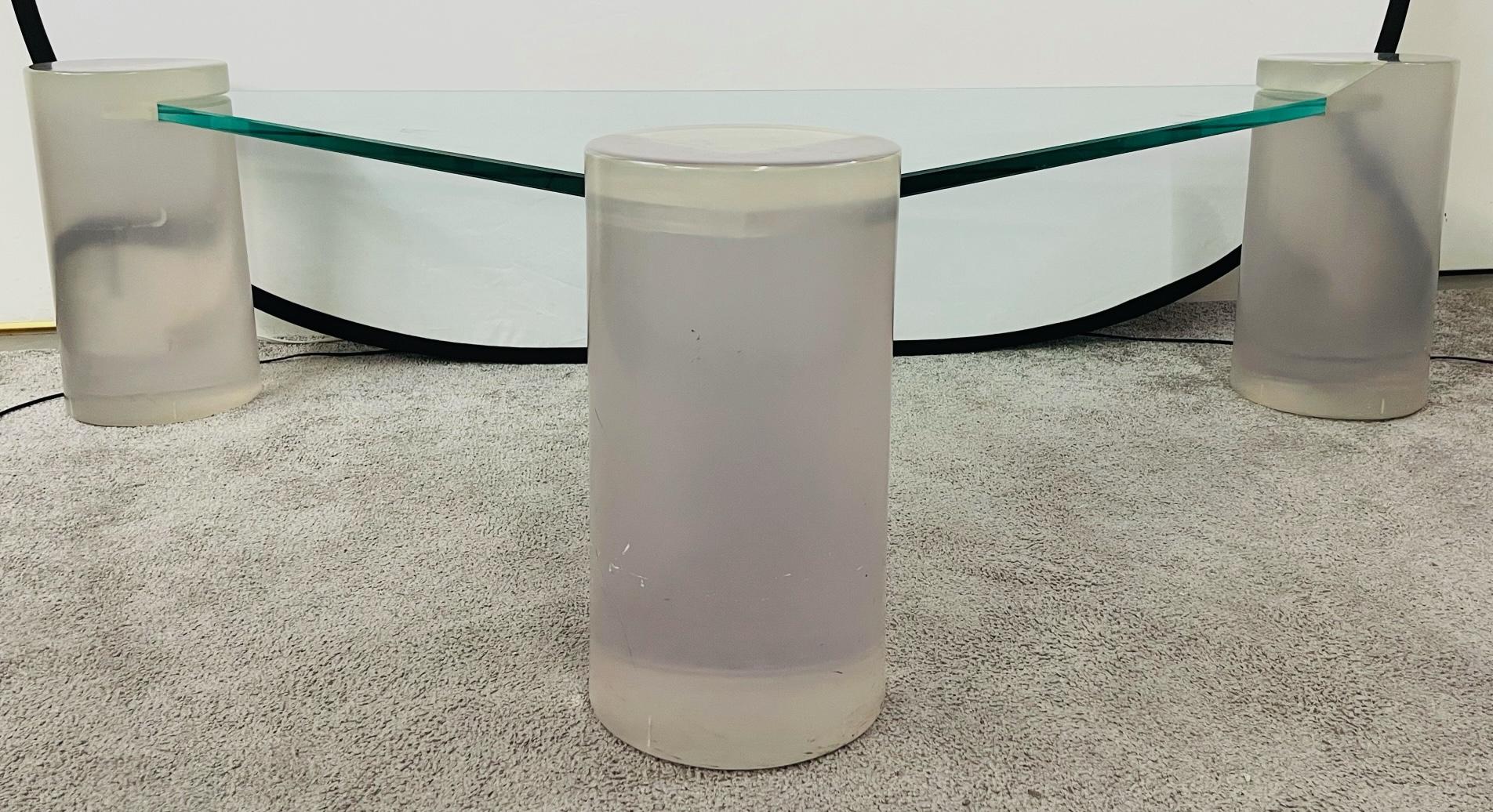 A stylish and timeless triangle glass top and Lucite coffee table in the manner of Karl Springer. . Each cylindrical corner is made of thick Lucite in a light purple tone. The top glass is inserted and supported by the three Lucite feet/ corners.