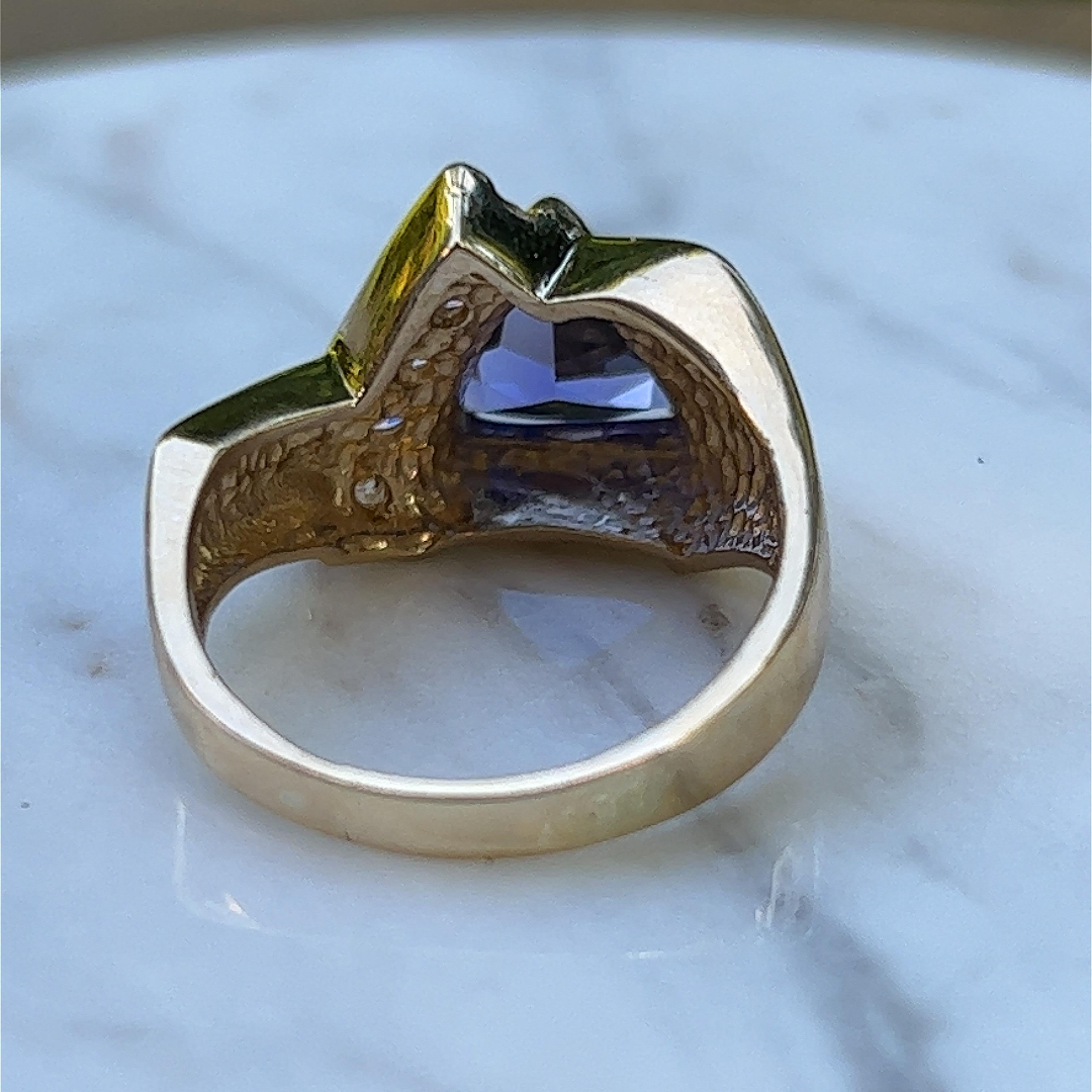 Ein Ring aus 14-karätigem Gelbgold, besetzt mit einem 6,5 mm großen dreieckigen Tansanit und fünf runden Diamanten im Brillantschliff mit einem Gesamtgewicht von ca. 0,12 Karat, Farbe J/K und Reinheit SI.  Der Ring hat die Fingergröße 6,5.  