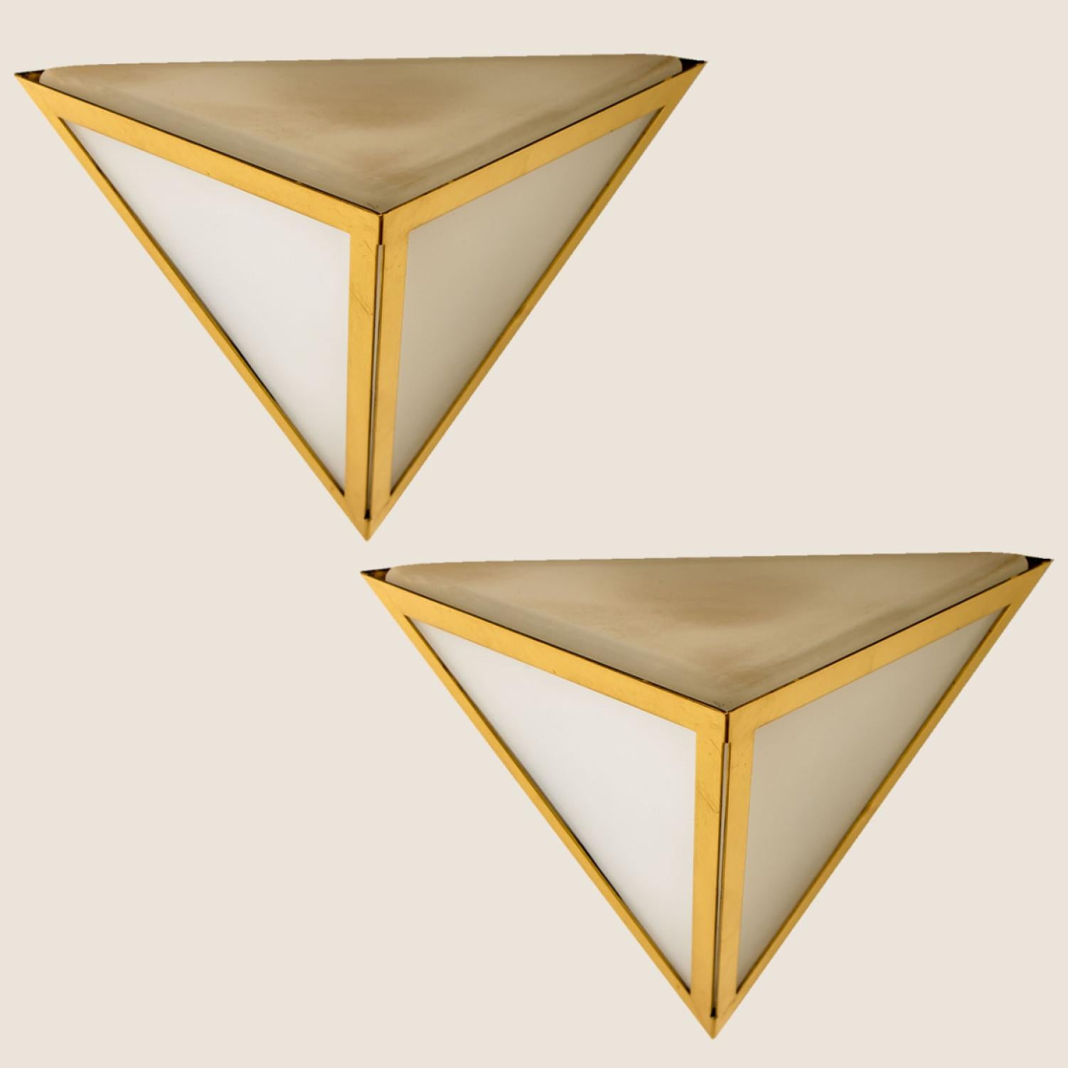 Triangle shaped wall lights in white opaline glass with brass details. Manufactured by Glashütte Limburg in Germany during the 1970s. (early 1970s). Nice craftsmanship. Minimal, geometric and simply shaped design.

Please note the price is for one