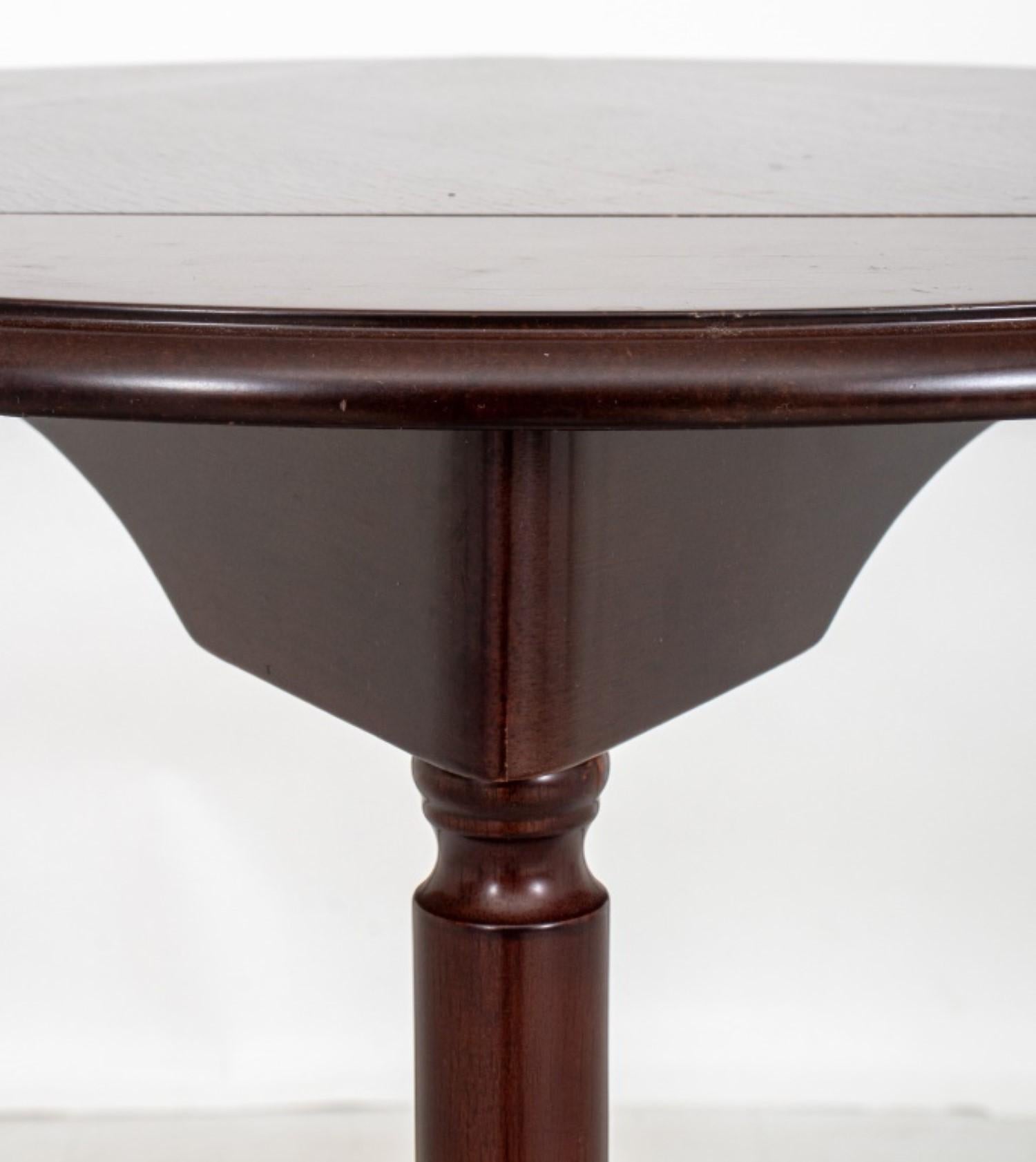The triangular handkerchief table is made of mahogany-stained wood and features a triangular drop-leaf top. It stands on three tapering columnar legs that terminate in pad feet. When closed,

Dealer: S138XX
