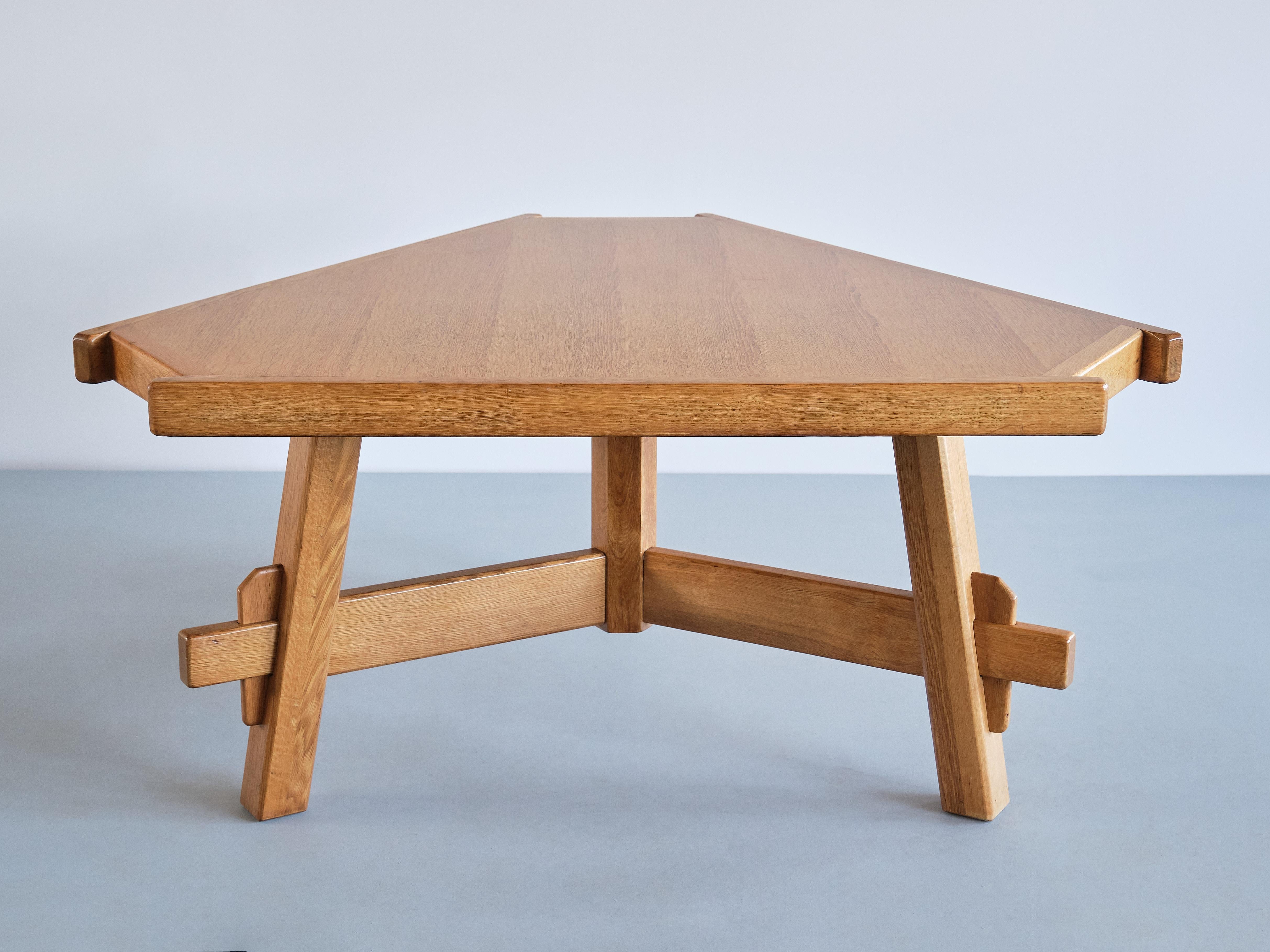 This rare geometric dining table was produced in France in the 1960s. The striking design is marked by the triangular shape of the top and frame. The table is entirely executed in a solid blonde oak wood. The top rests on three legs which are
