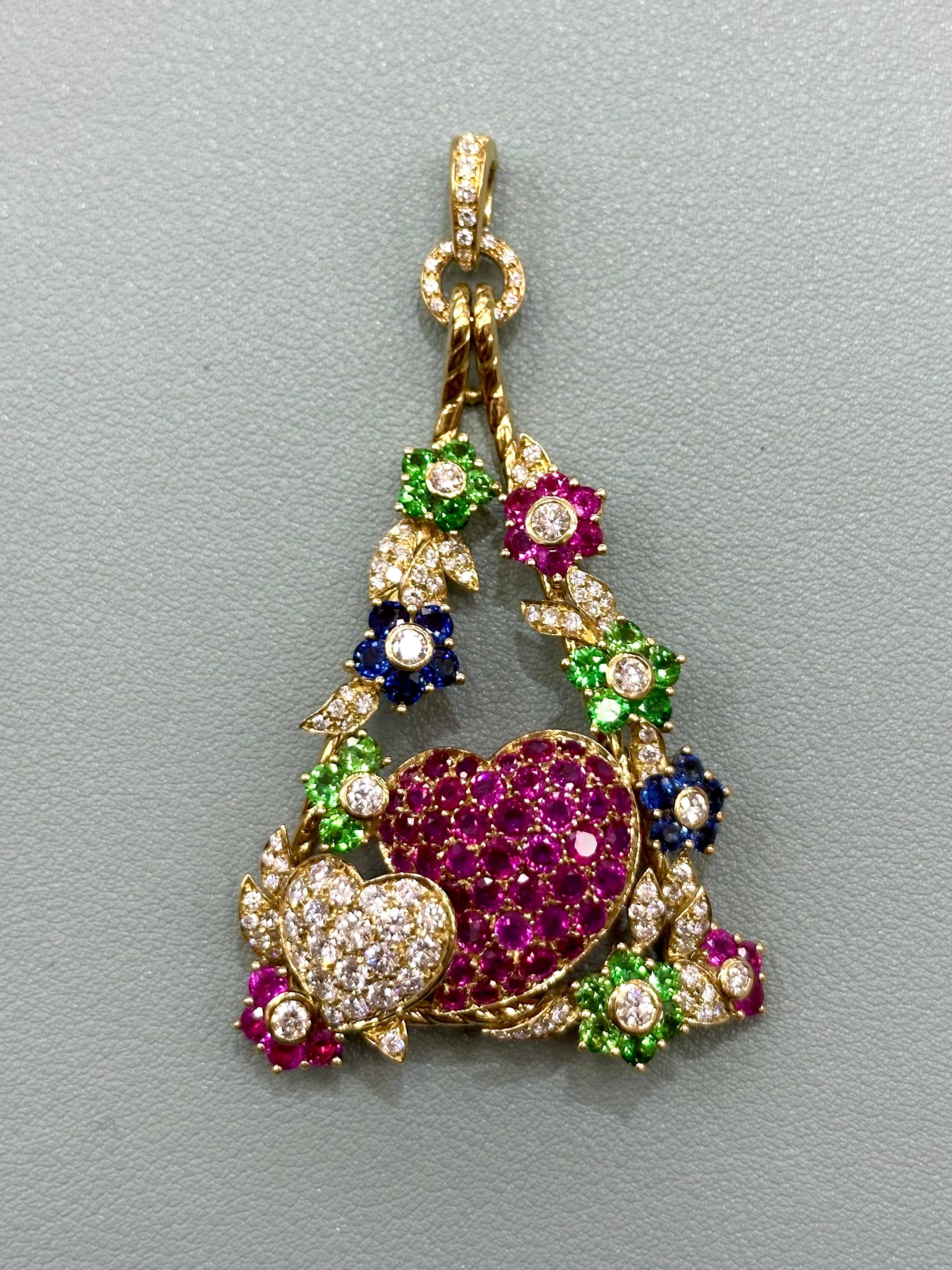 Dreieckiger Anhänger mit Diamantblättern, Blumen aus rosa, blauen und grünen Saphiren und zwei Herzen aus Diamanten und rosa Saphiren, gefasst in 18 Karat Gelbgold. 

Gewicht des Diamanten: 3,20cts 

Gesamtgewicht: 28,64 Gramm