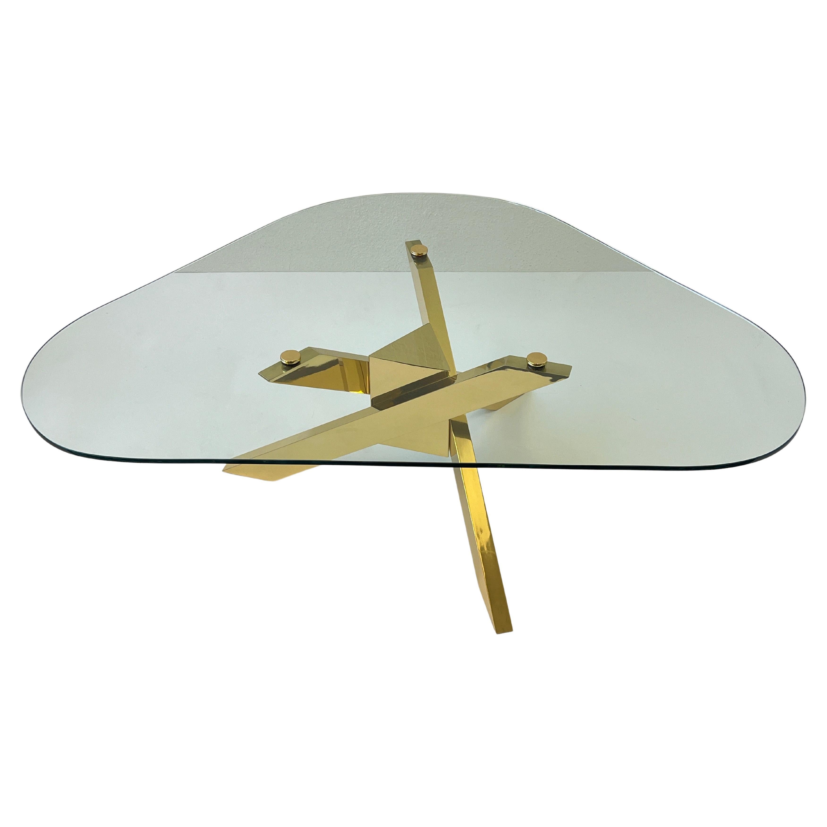 1970’s Triangular shape glass top with a polish brass tripod base cocktail table. 
The base has been newly professionally polished and lacquered. The 1/2” thick glass is original with two small scratch, consistent with age. 

Measurements: 50”