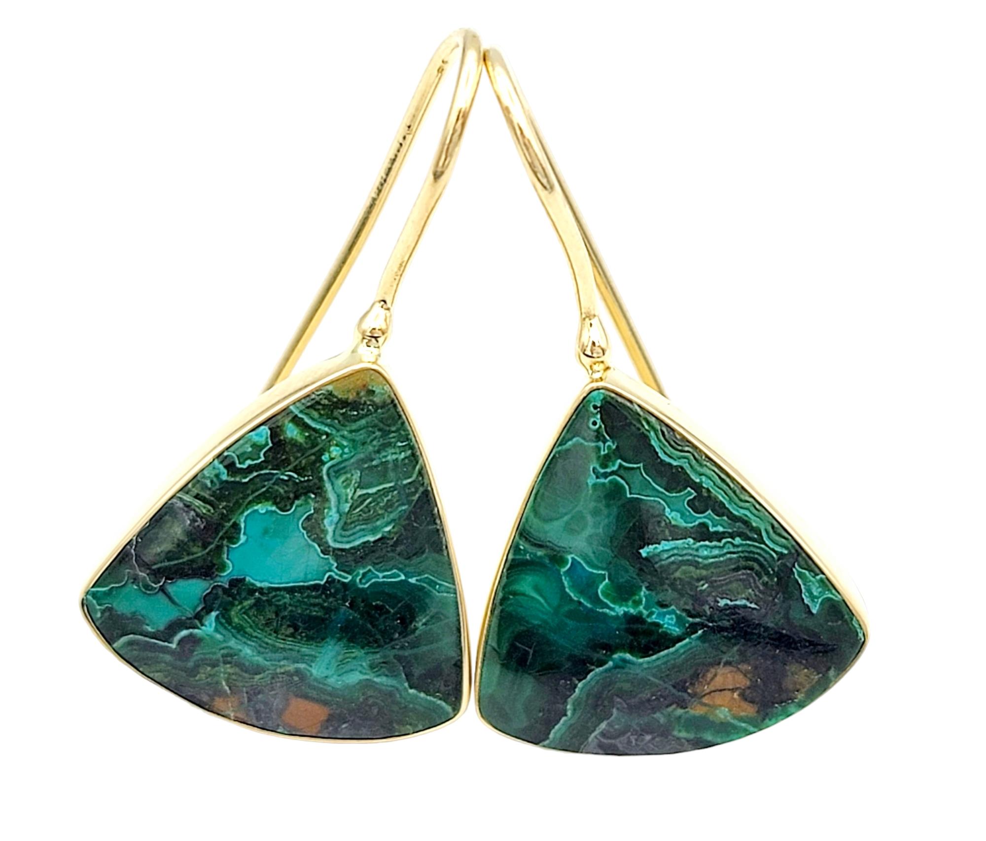 These green malachite gemstone earrings are a true testament to nature's beauty, elegantly captured in a rounded triangular shape and cradled within exquisite 14 karat yellow gold bezel settings. The combination of rich, forest-green malachite and