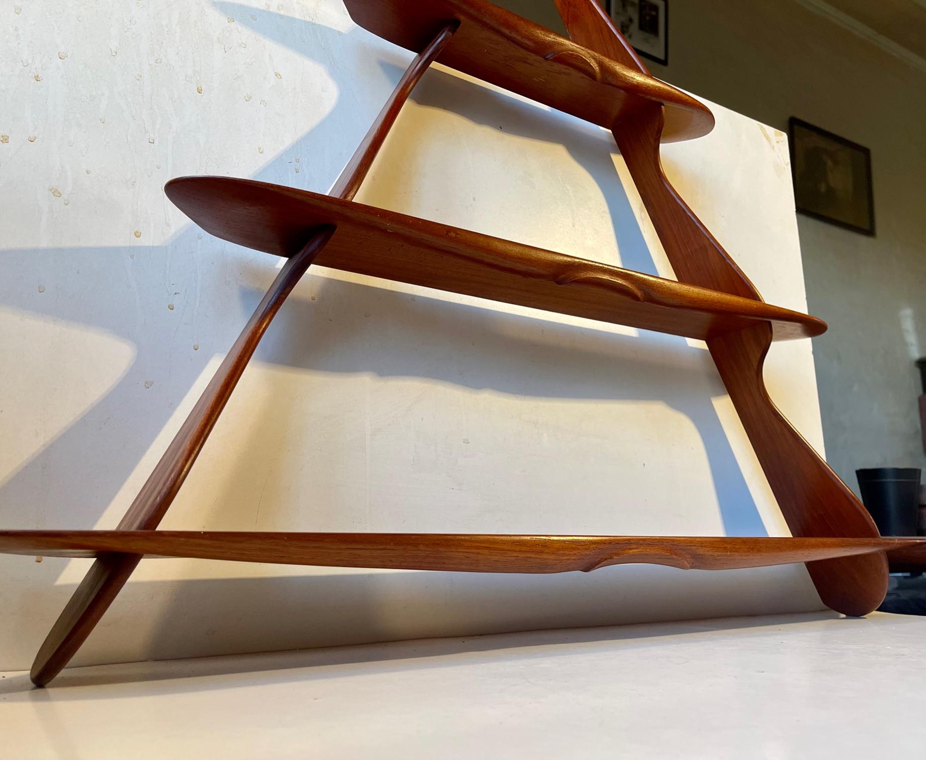 Small triangular wall shelf in solid teak. Assembled without the use of metal. Beautiful organically shaped profiles. This design is attributed to the most eccentric and detail oriented Danish Design master Peder Moos. Whether or not he had his