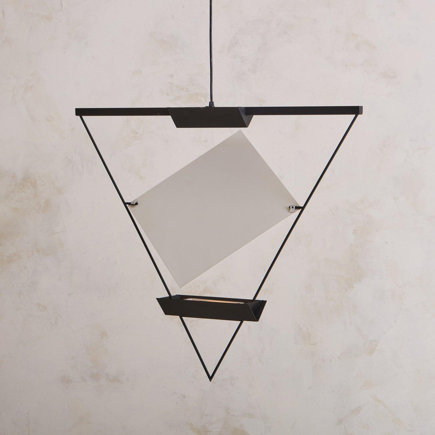 Diese dreieckige Pendelleuchte wurde in den 1980er Jahren vom Schweizer Architekten Mario Botta (geb. 1943) für Artemide entworfen. Sie besteht aus einem schwarz emaillierten Metallrahmen, der zwei Halogenlampen beherbergt. Ein verstellbares weißes,