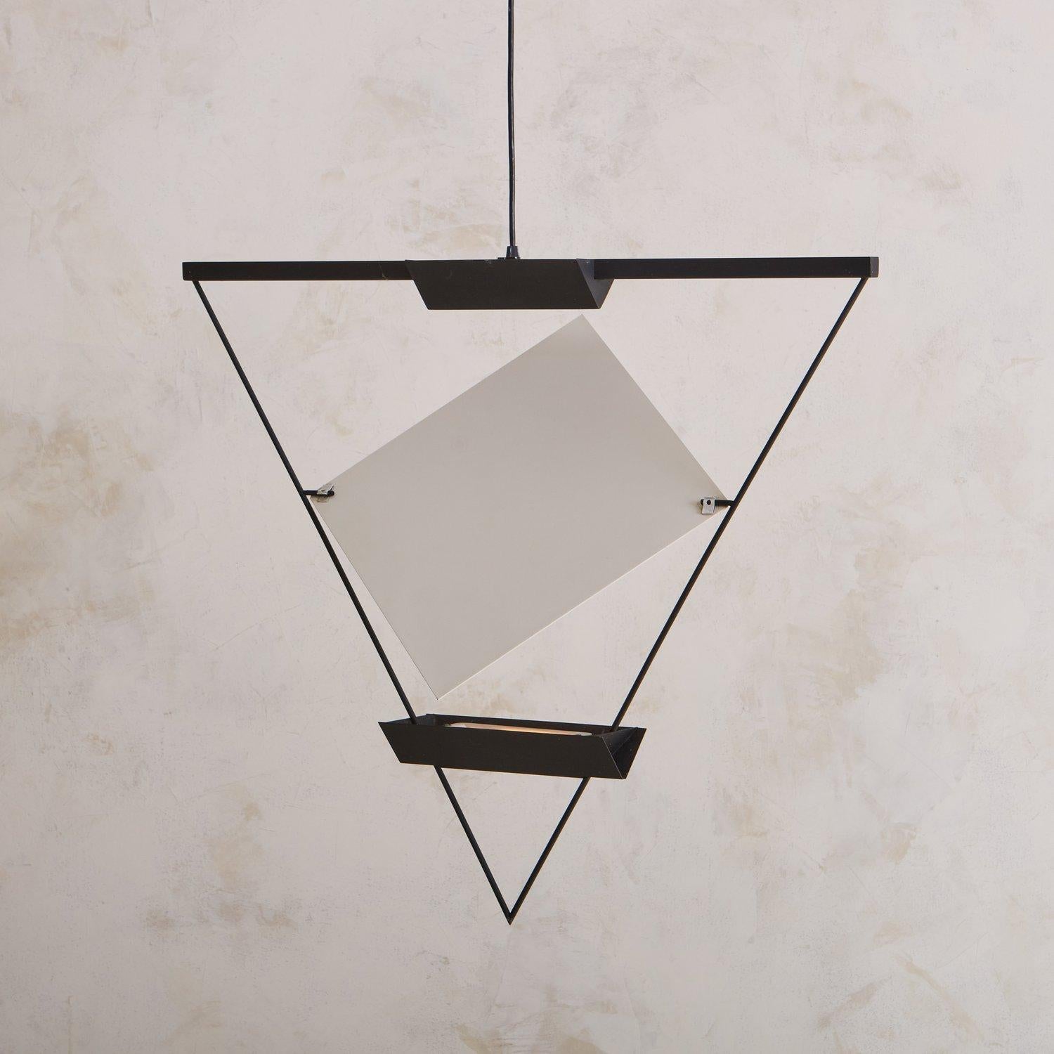 Disegnata dall'architetto svizzero Mario Botta (nato nel 1943) per Artemide negli anni '80, questa lampada a sospensione triangolare ha una struttura in metallo smaltato nero che ospita due lampadine alogene. Un pannello bianco regolabile a forma di