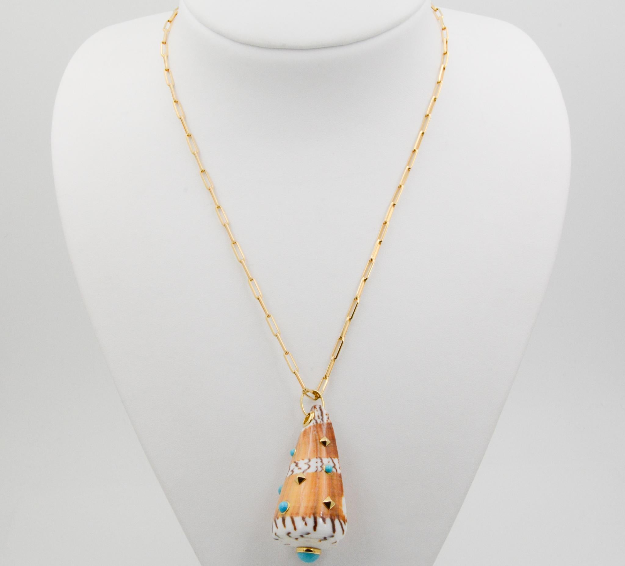 From Seaman Schepps, this General Cone Shell pendant features turquoise and 18 karat yellow gold squares with grommet and bail set in yellow gold. The pendant measures at 50x26mm. 
The pendant hangs on a 27 inch long 18 karat yellow gold paperclip