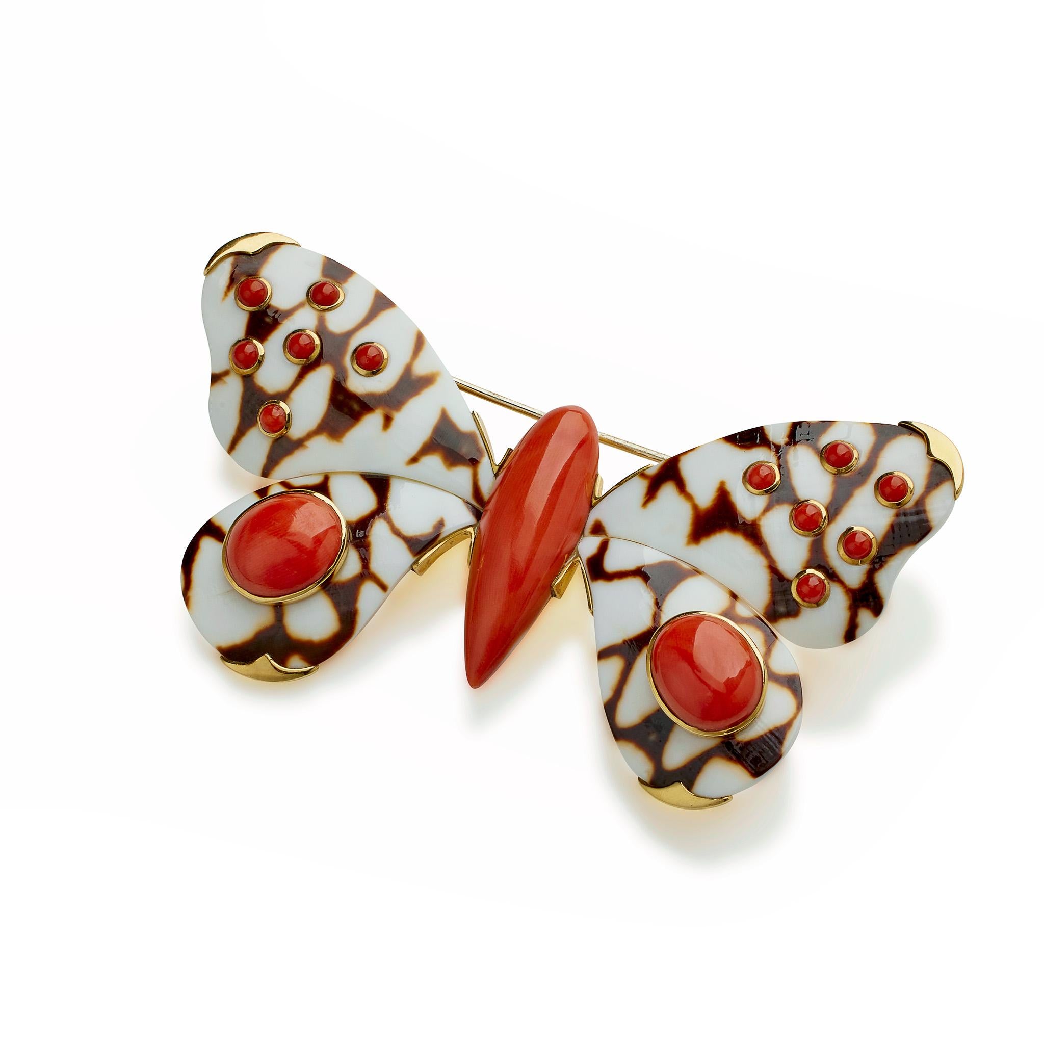 This contemporary Trianon butterfly brooch is composed of shell, coral and 18K Gold. It is designed as a butterfly with coral body and carved brown on white patterned shell wings set with coral cabochons, mounted in 18K gold. Beautifully made, this