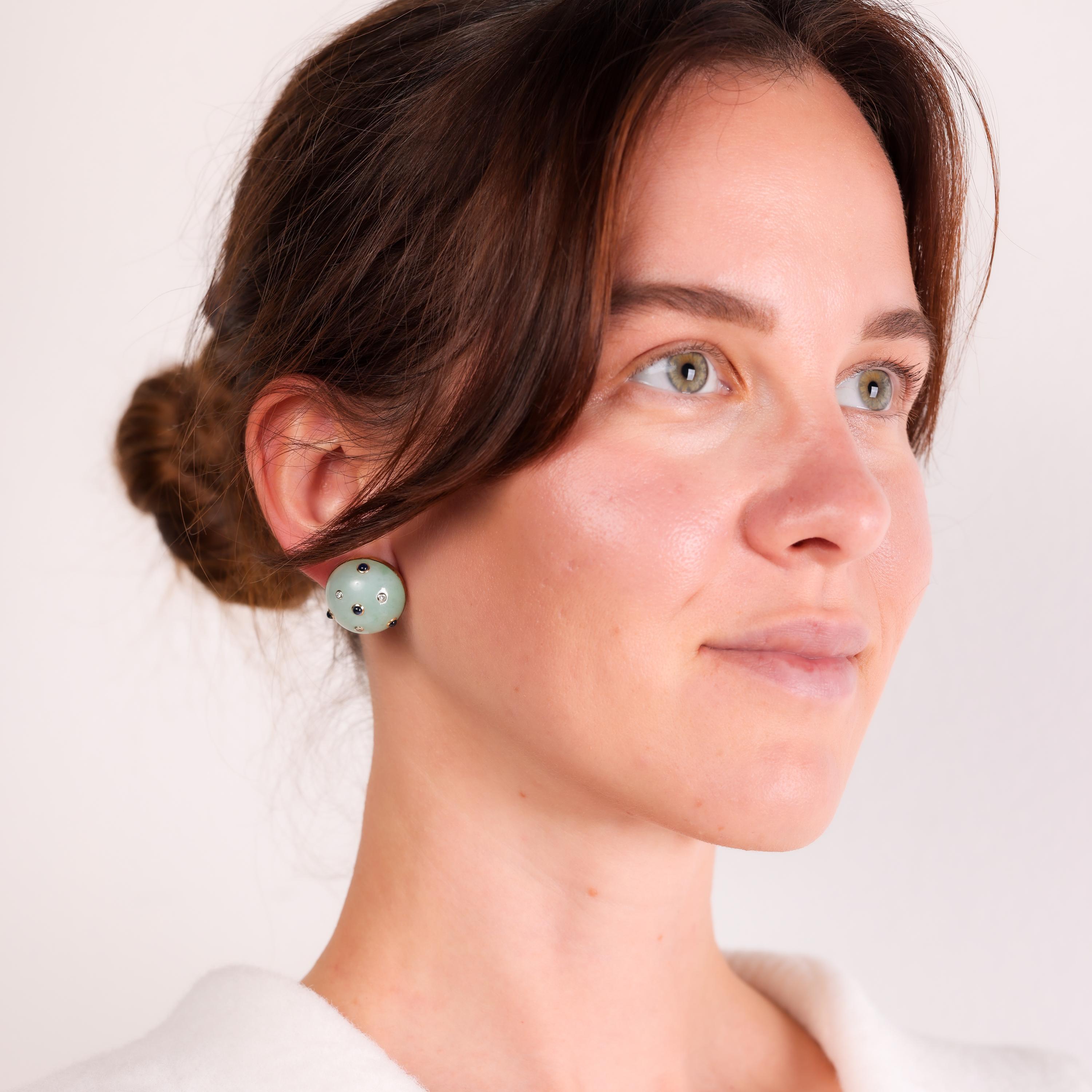 These vintage Trianon clip-on earrings showcase stunning jadeite cabochons surrounded by vivid sapphires and sparkling diamonds, all set in luxurious 14k yellow gold.

Brand: Trianon
Center stone: 2 cabochon cut milky light greenish jadeites
Size: