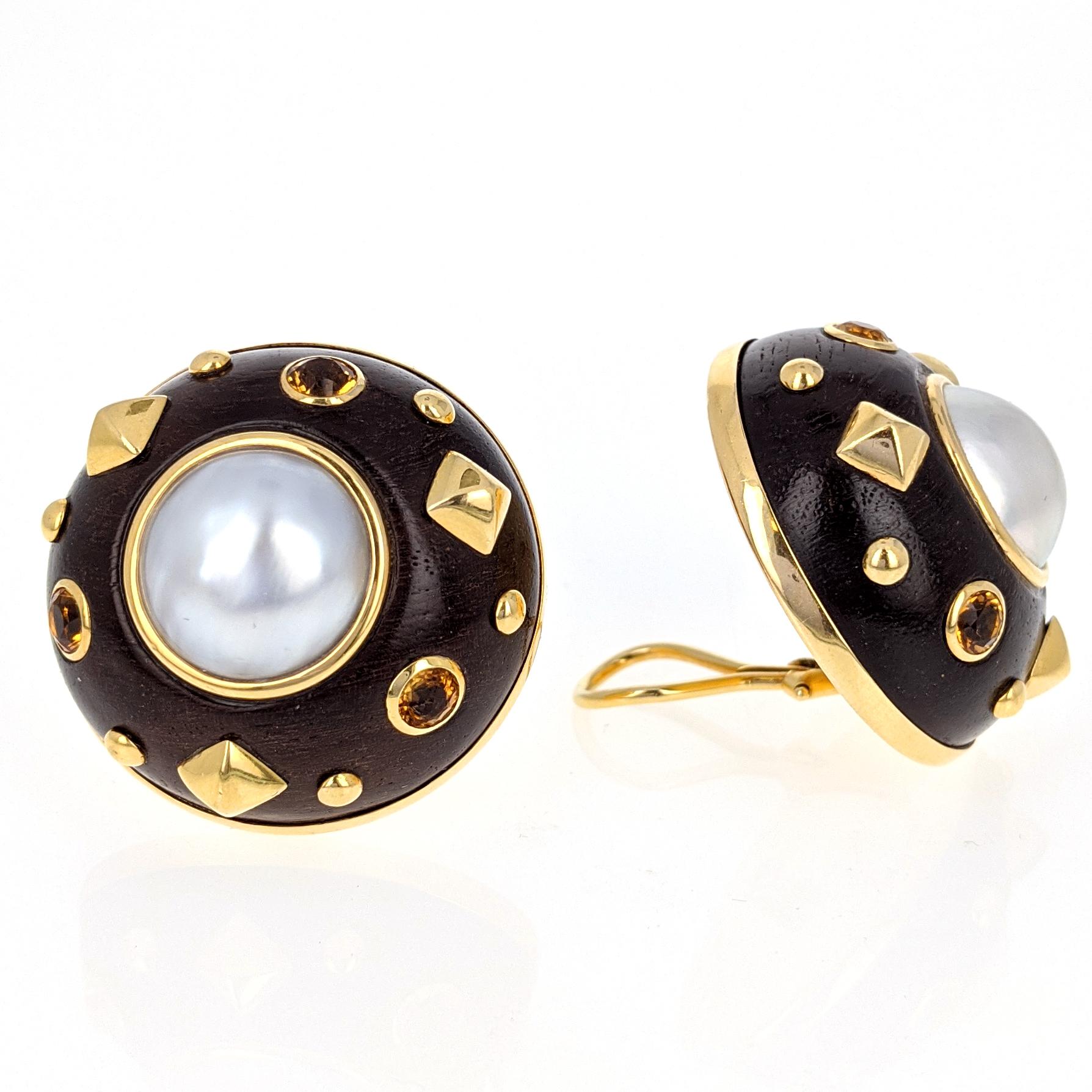 This pair of clip earrings by Trianon centers upon bezel set mabe pearls. Each is set within a bombe wood frame with round-cut citrines and round and pyramidal 18 karat yellow gold accents. They measure 1.25 inches in diameter. They are marked