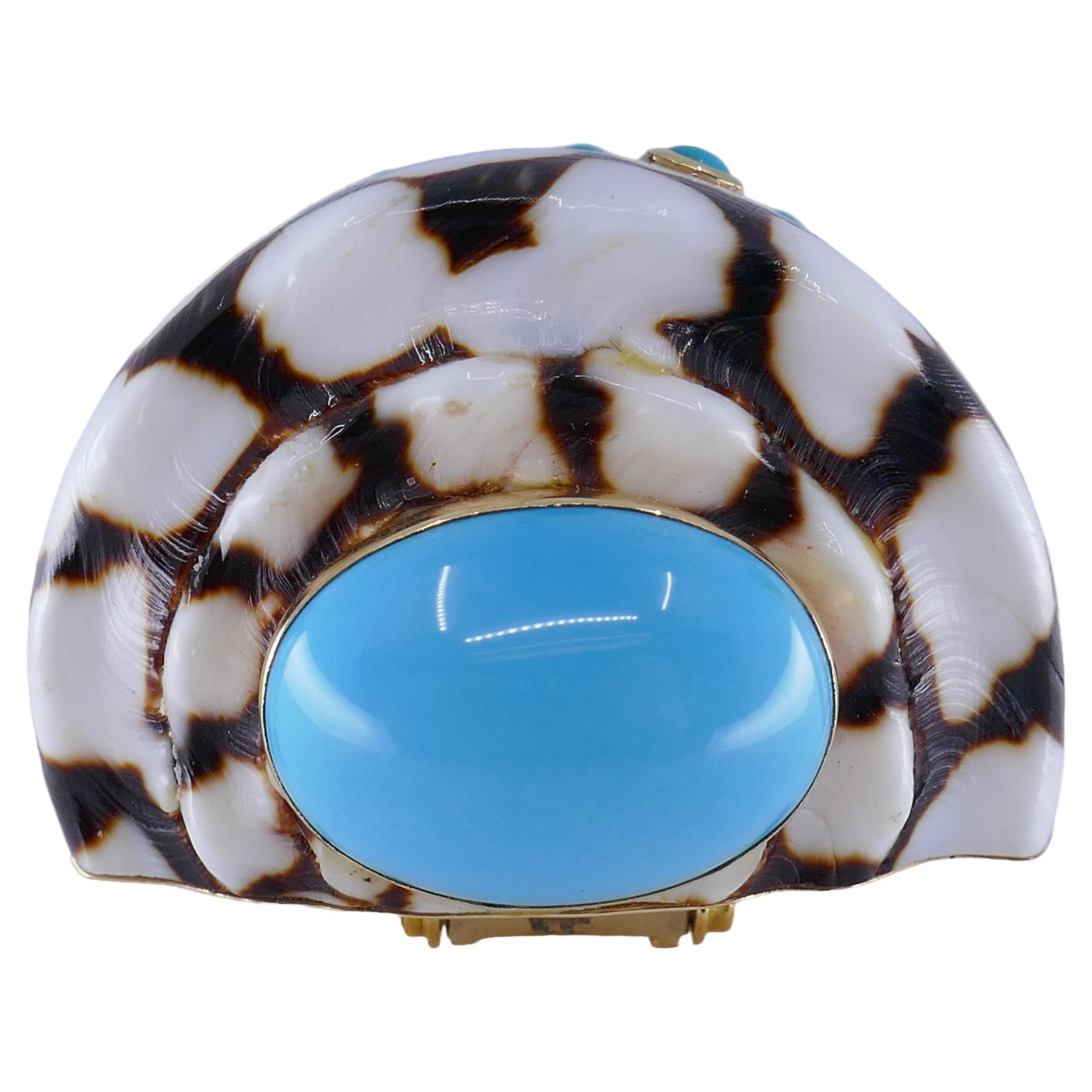 A striking shell brooch by Trianon, made of 14k gold, features cabochon turquoise.
Designed as a cone with a large turquoise on the bottom. Ten small, bezel set turquoises are mounted on the surface of the brooch. The gems look like they grew on the