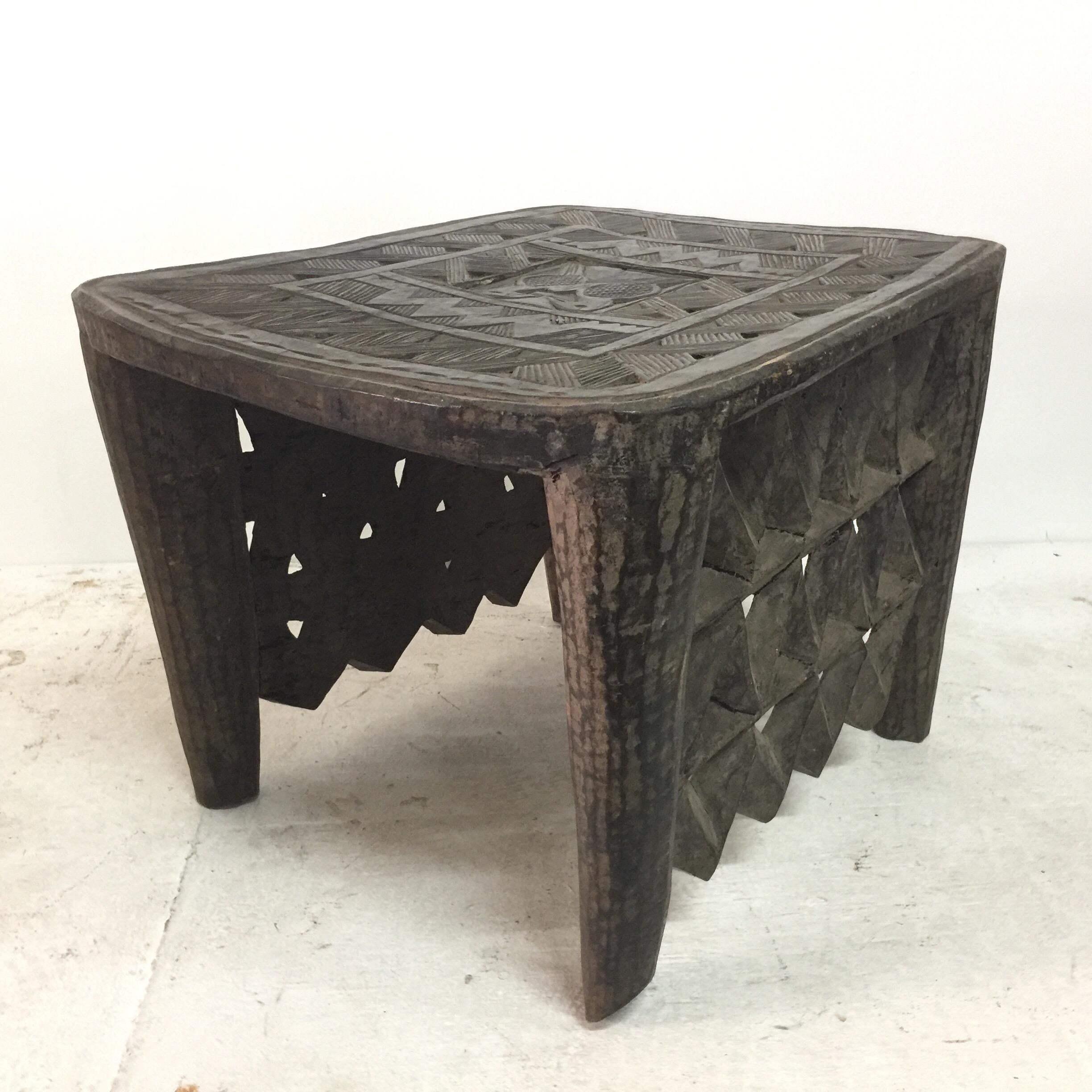 This beautifully carved African tribal table has two lateral sides fully carved to floor and two open sides (see detail images). The center top has a hidden compartment. Great as a bench or side table!