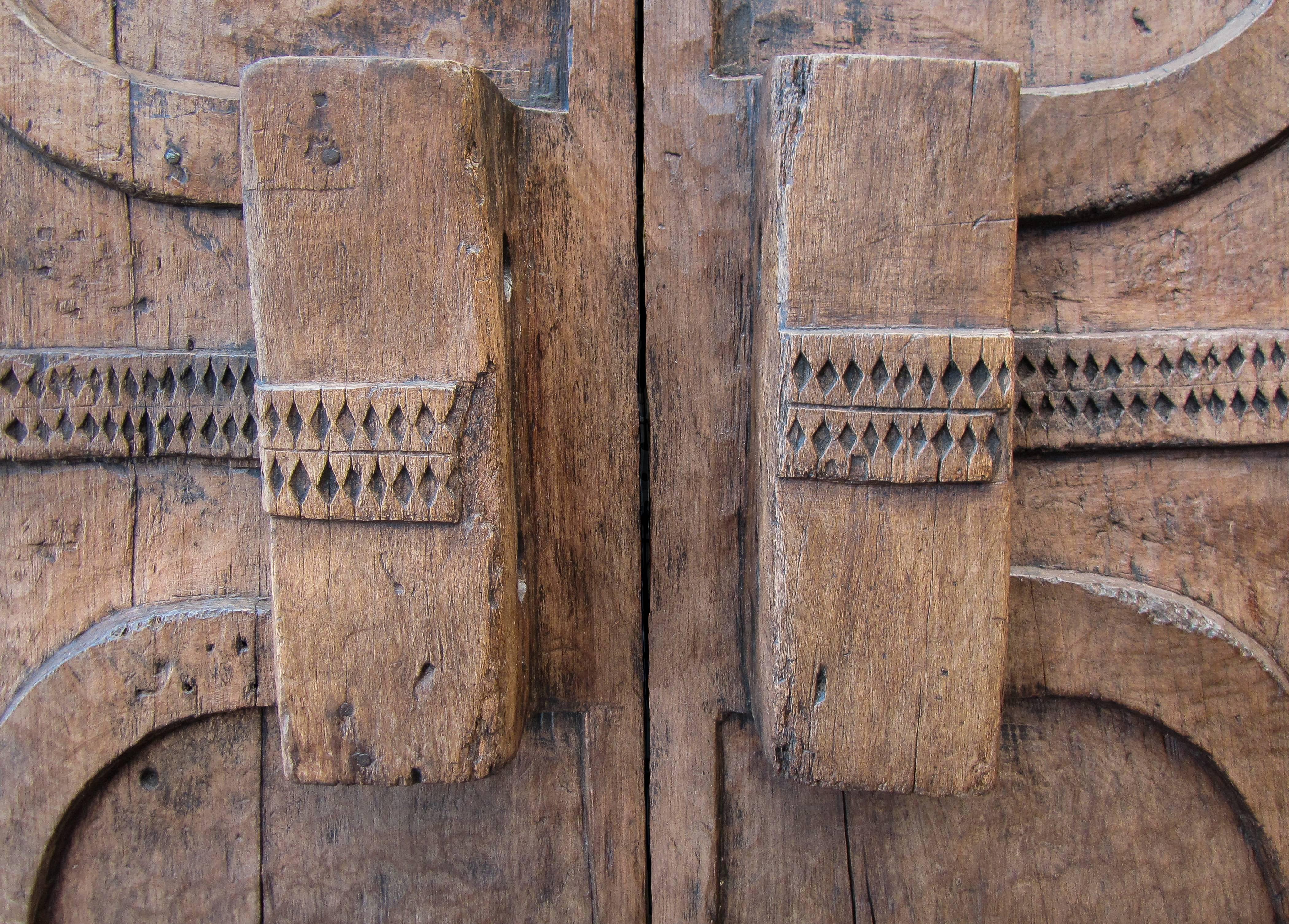 This exceptional piece is one of the few impressively carved granary doors which have survived to our days. Created in the village of Wakching, in the Indian state of Nagaland, it evinces two central cylinders at each wing through which two tapering