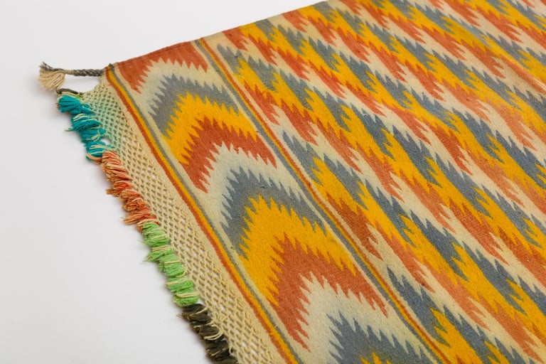 Handwoven cotton tribal Dhurrie rug with bright yellow red and blue optic pattern.
Hand knotted fringe on both ends. Rajasthan, India.