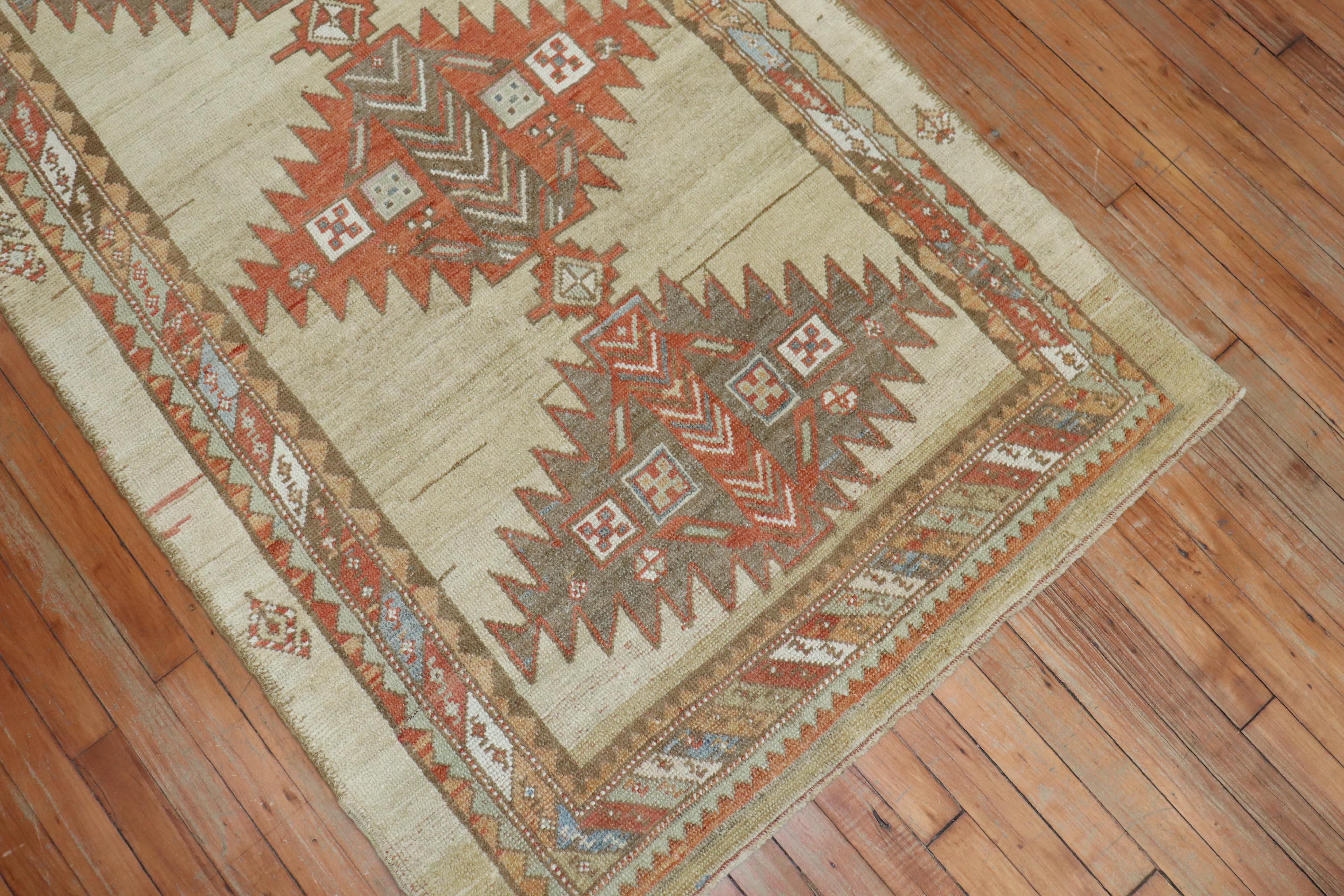 An early 20th century Persian Serab rug with a large scale tribal design on a soft camel colored ground. Accents in brown, terracotta, light blue and rust. The rug has a very soft and casual feel. The Pile is sturdy and can with stand heavy day to