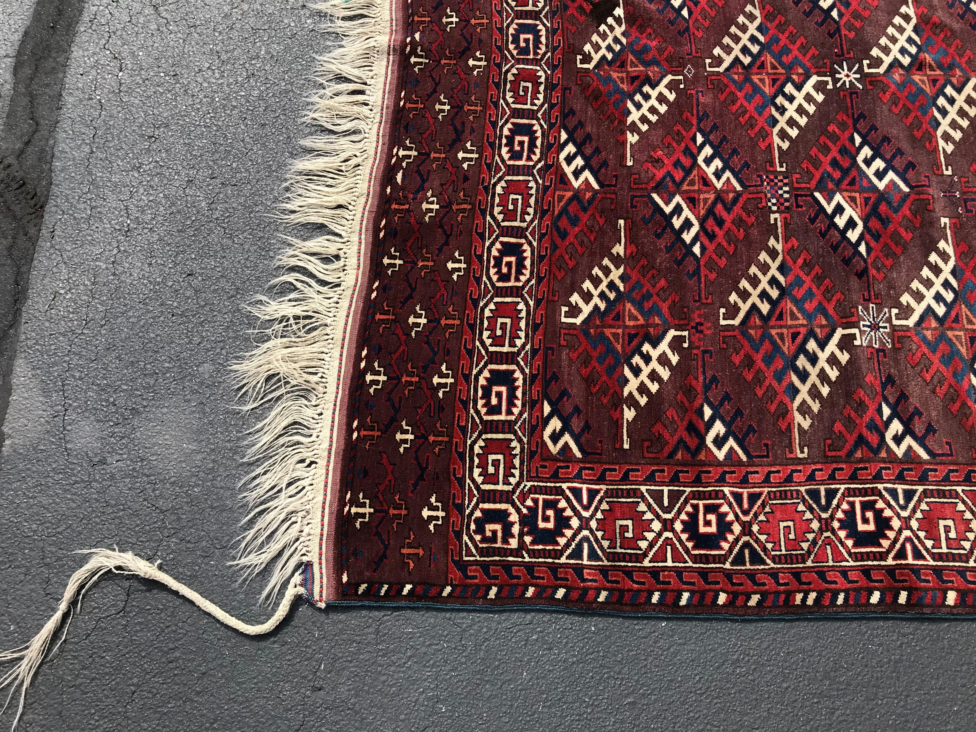 A fine tribal Caucasian room size wool rug on a deep red or cherry field with an unusual pattern, in very good overall condition, maintaining its original long fringes, with minimal imperfections and no wear. The rug dates to circa 1930s.