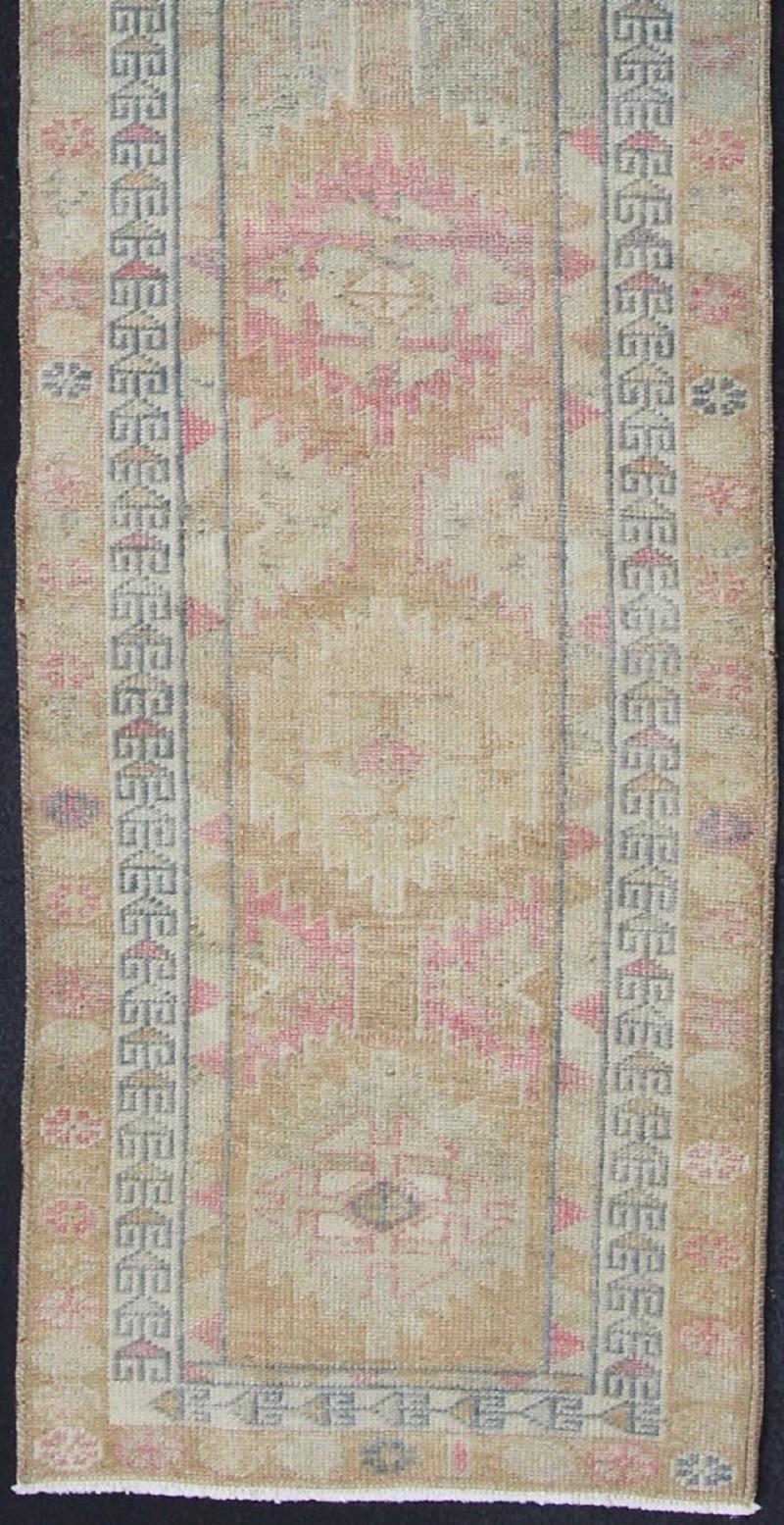 Oushak runner with tribal motifs in blue and pink, rug en-165353, country of origin / type: Turkey / Oushak, circa 1960

This Oushak runner from Turkey is characterized by a neutral-toned background and an assortment of tribal designs and flowers in