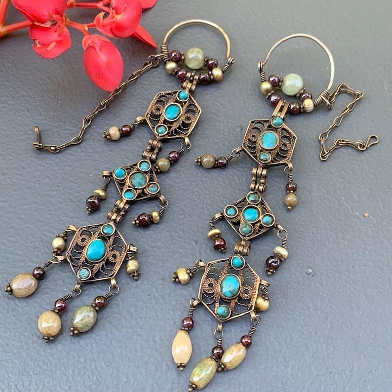 A remarkable pair of antique earrings from the first half of the 20th century, hailing from the rich cultural heritage of Bukhara, Uzbekistan. These ethnic tribal earrings are finely crafted in gold-gilded silver and feature genuine gemstones,