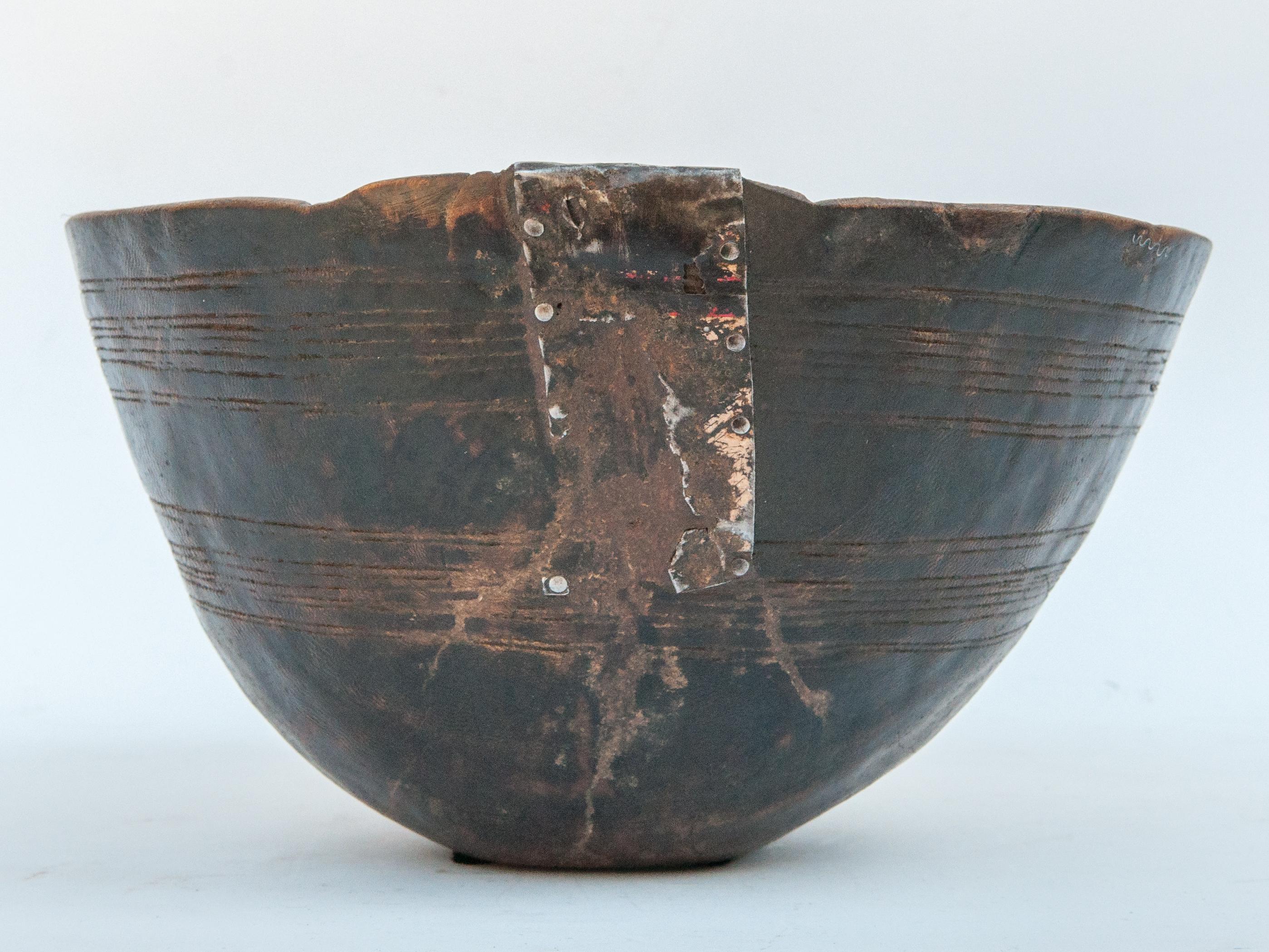Tribal handhewn wooden bowl with original metal repair. From the Fulani people of Niger, mid-20th century.
Offered by Bruce Hughes.
This rustic wooden bowl was fashioned by hand from a single piece of wood using very basic tools. Original metal