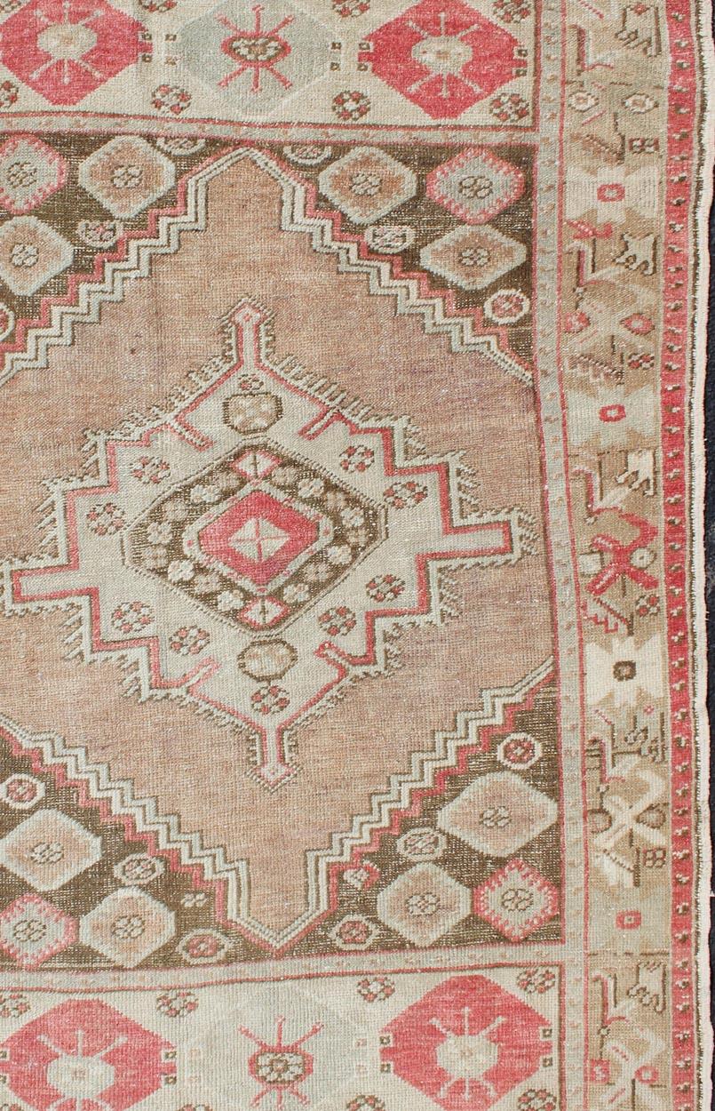 Tan, earth tones and coral pink tribal medallion design unique Oushak vintage rug from Turkey, rug EN-179009, country of origin / type: Turkey / Oushak, circa 1920.

This magnificent vintage Turkish Oushak displays a glorious and unique coloration