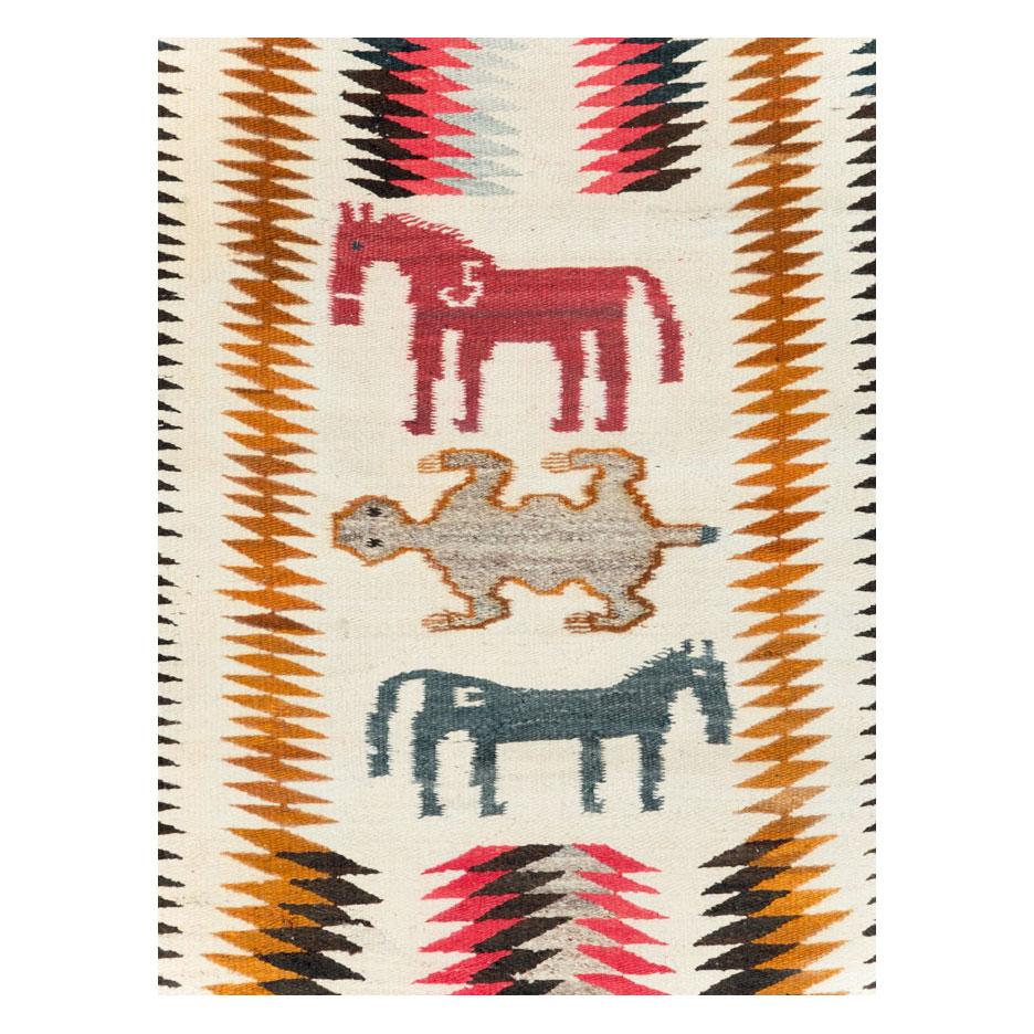 Ein alter amerikanischer Flachgewebe-Teppich, der Mitte des 20. Jahrhunderts vom Navajo-Stamm handgefertigt wurde und ein bildhaftes Tiermotiv aufweist.

Maße: 3' 3