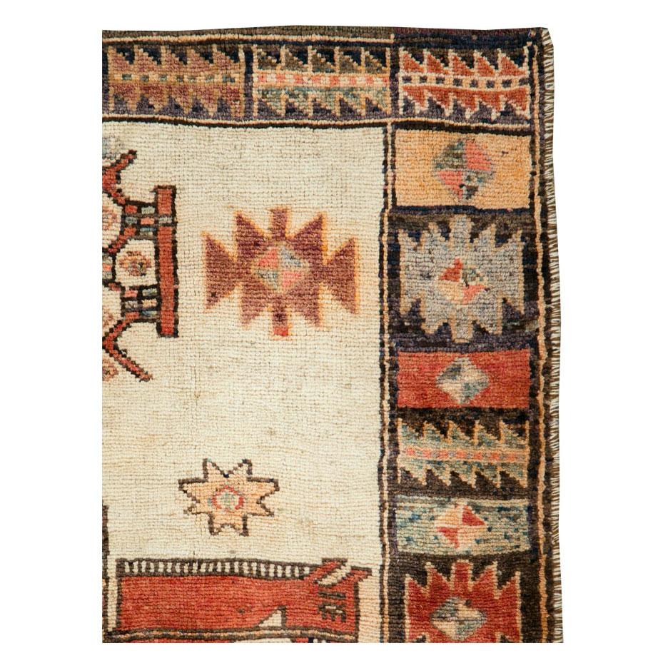 A vintage Persian Pictorial accent rug in square format handmade by the Bakhtiari nomadic tribe during the mid-20th century with a pictorial design of an androgynous figure on horseback over a cream field encompassing various tribal