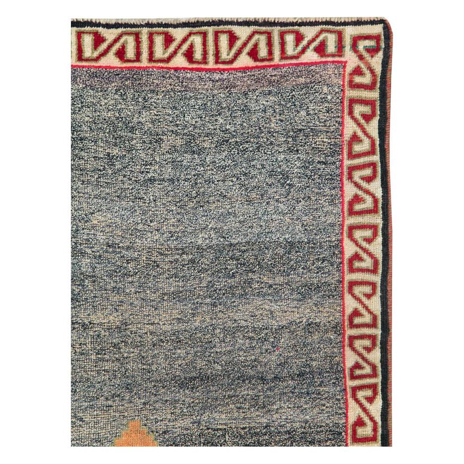 A vintage Persian Gabbeh accent rug handmade during the mid-20th century with a tribal 'salt and pepper' design in black, cream, and blue, with once central medallion in rust orange.

Measures: 3' 9