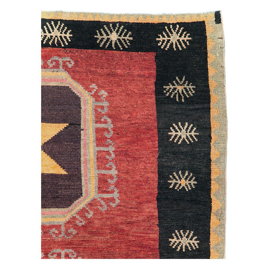 A vintage Turkish Anatolian accent carpet handmade during the mid-20th century with a large-scale geometric tribal design over a field in shades of red and a black border.

Measures: 6' 7