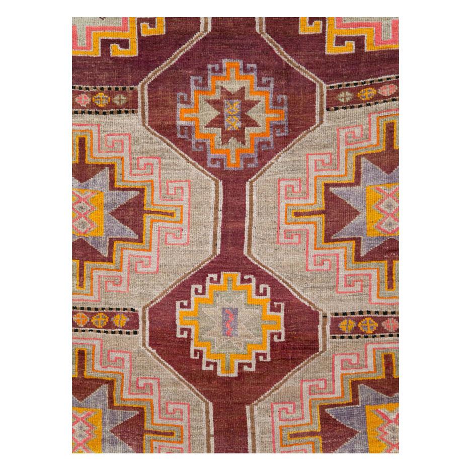A vintage Turkish Anatolian room size carpet handmade during the mid-20th century with a large-scaled open field tribal design over a marsala colored field.

Measures: 8' 5