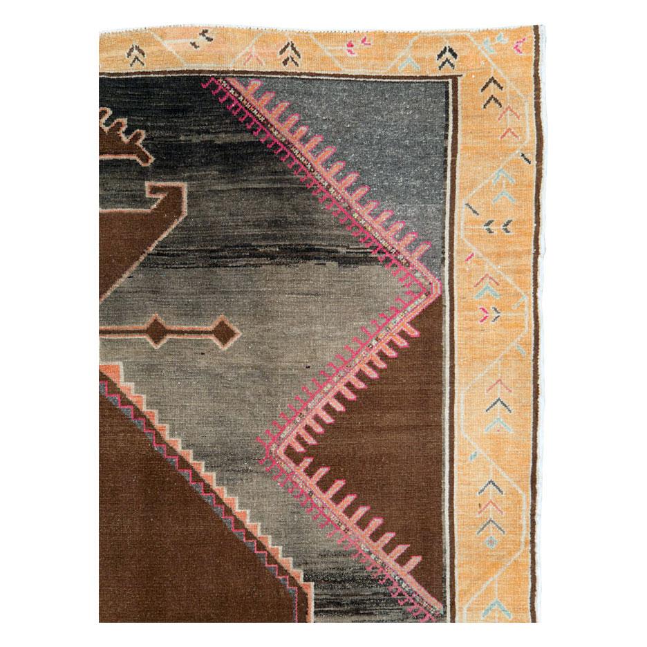 A vintage Turkish Anatolian room size carpet handmade during the mid-20th century with a large and open scale tribal design. The large brown medallion is divided from the gray and brown striated field by a stepped coral/orange and pink