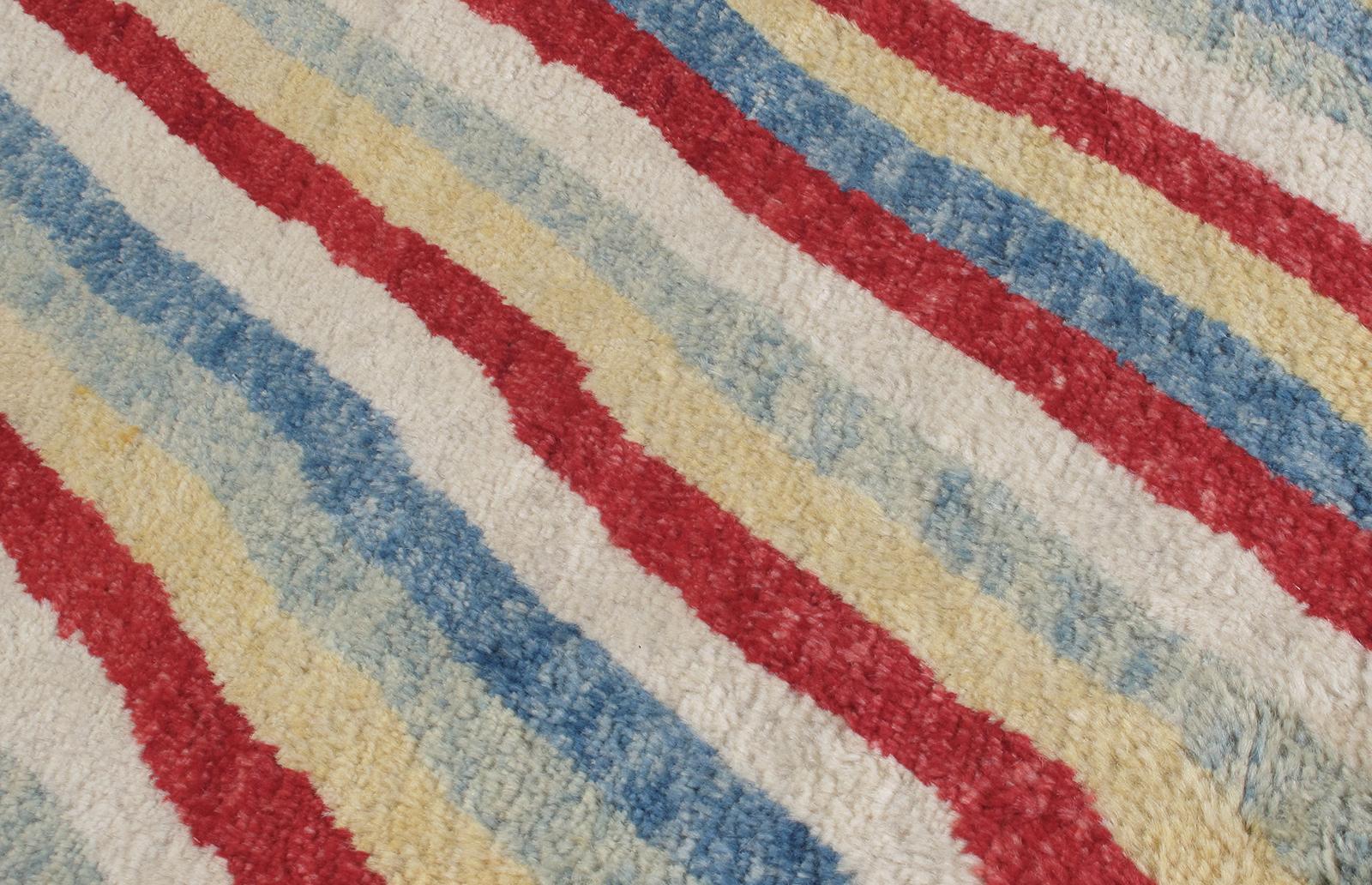 This tribal rug is made with 100% handspun Persian wool. It features a linear, diagonal design of bold colors. It is inspired by the vintage midcentury rugs that are native to the Shiraz region in Iran. Nasiri continues their rich tradition of rug