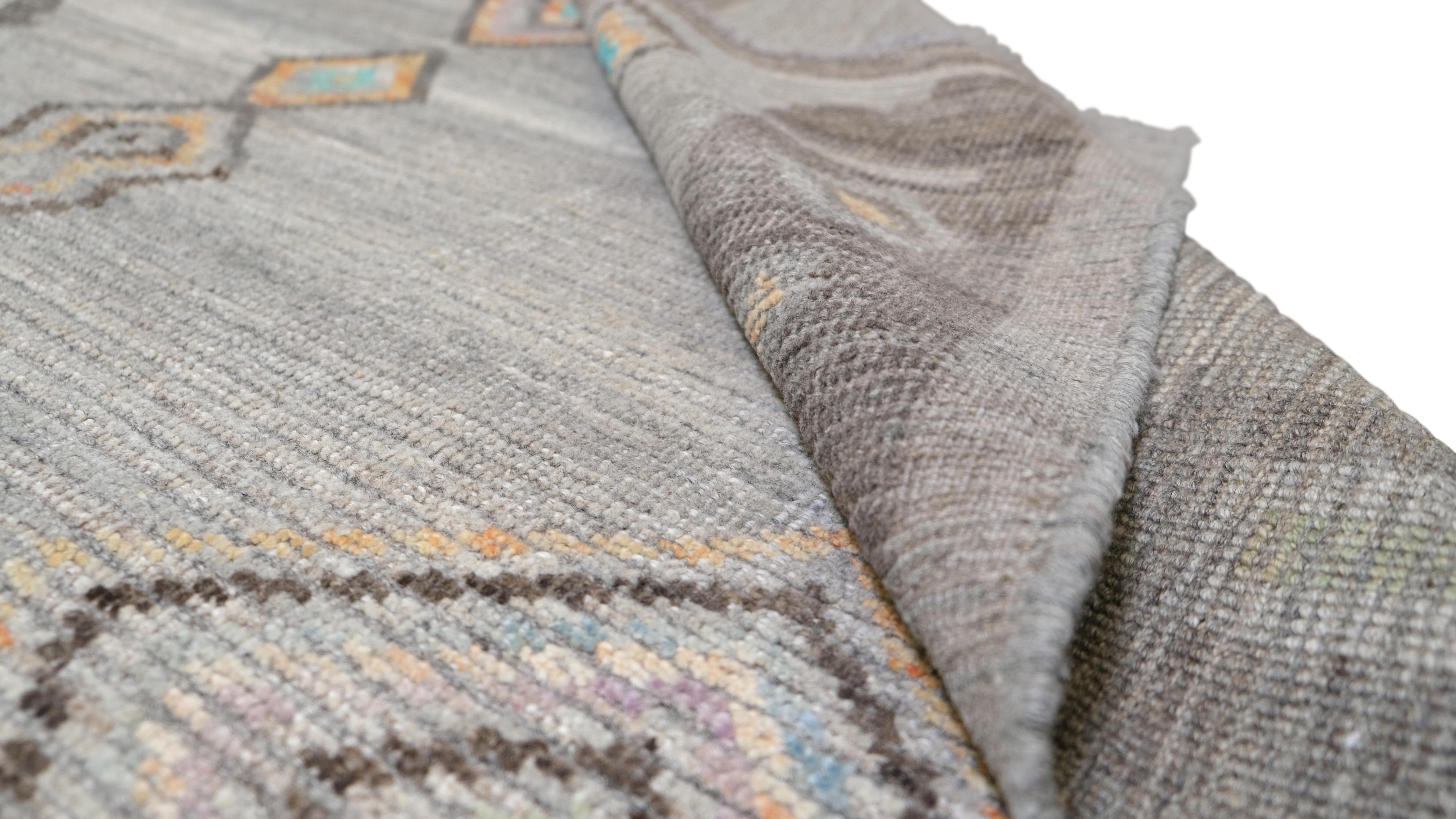 Infunde a tu espacio el encanto único de esta alfombra de lana anudada a mano. Con un llamativo diseño tribal geométrico, esta alfombra presenta un conjunto de motivos romboidales y sutiles dibujos abstractos, bellamente dispuestos sobre una base