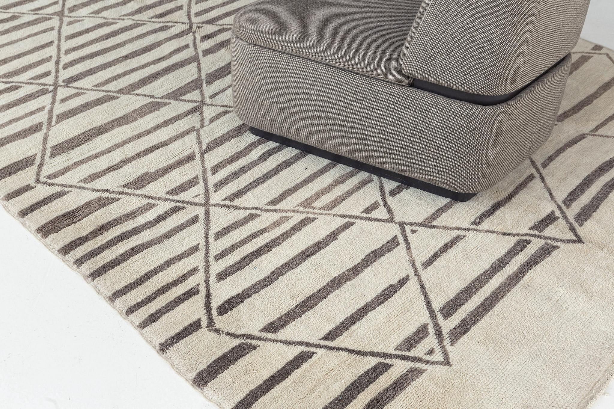 Questo bellissimo tappeto tribale marocchino emana raffinatezza e fascino. La trama in pile color avorio, ornata da elementi tribali color marrone chiaro, è un perfetto modello contemporaneo. Questo pezzo intrecciato a mano dona un'essenza