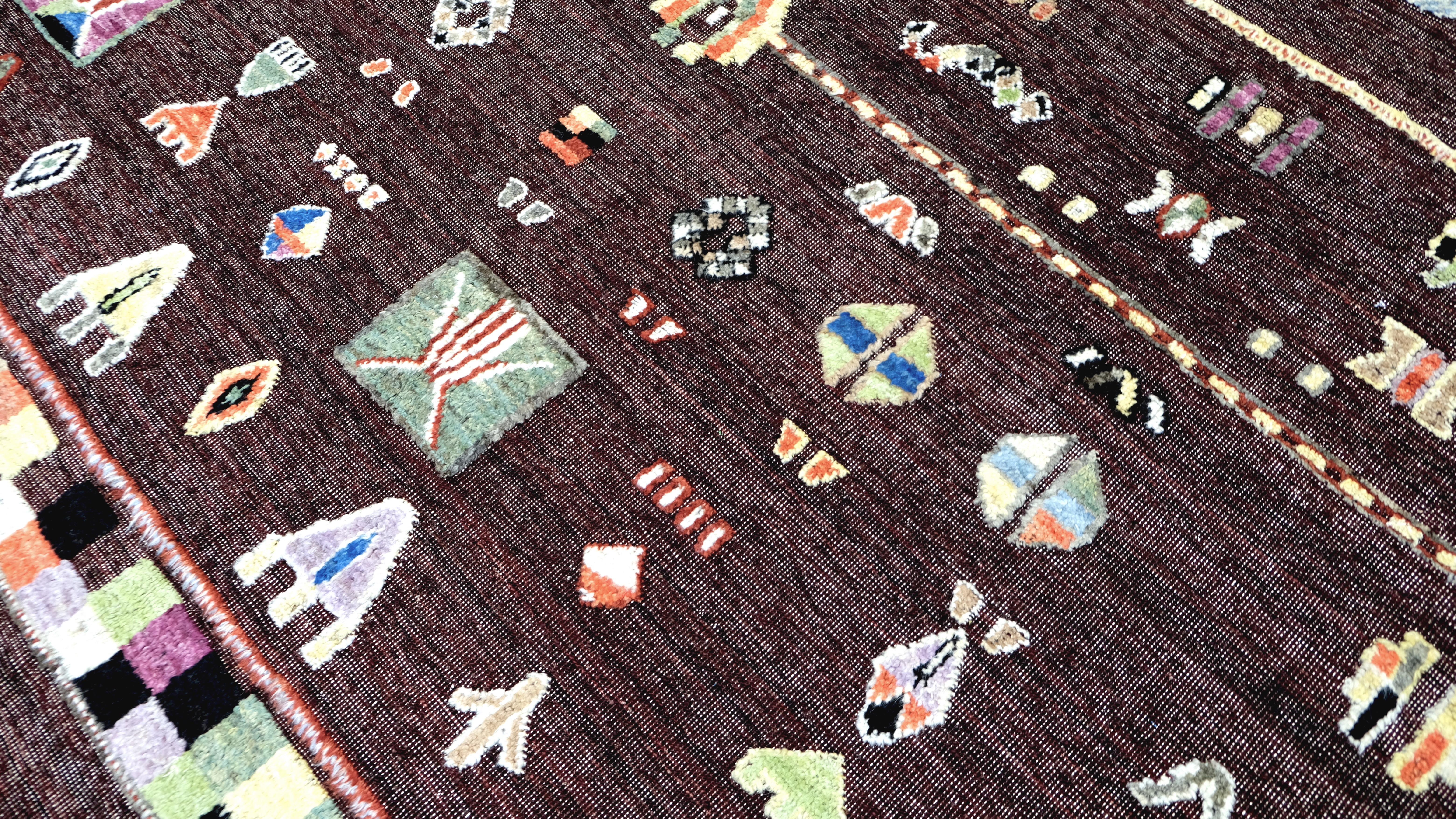 Transforma tu interior con la juguetona sofisticación de esta alfombra de lana anudada a mano. Con un intrincado diseño tribal abstracto multicolor, esta pieza ofrece una deliciosa mezcla de arte cultural y estética moderna. Sus tonos vibrantes pero