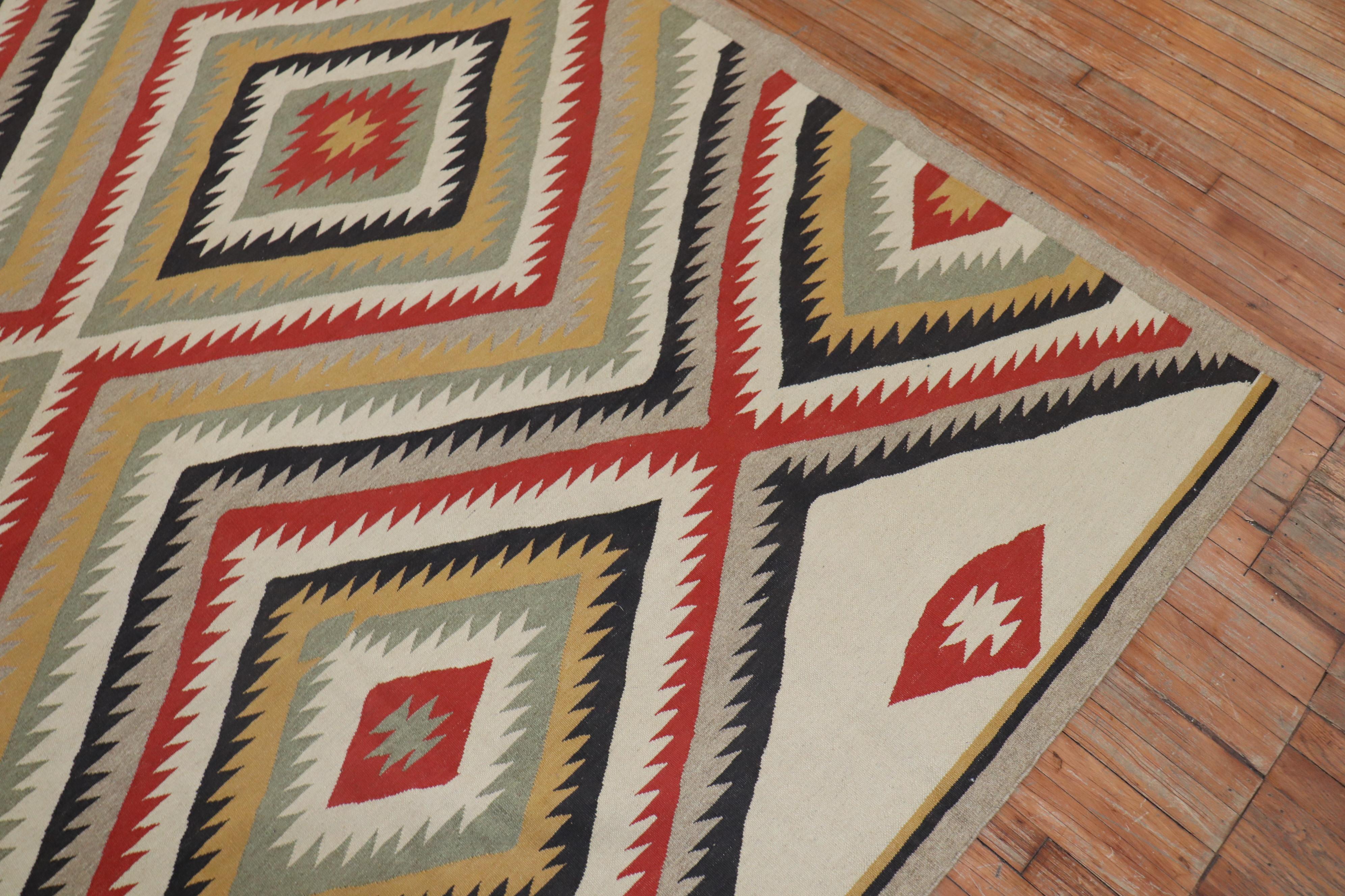 Une reproduction de tapis persan très décorative, unique en son genre, dérivée d'un tapis Navajo américain, avec un motif tribal géométrique à grande échelle. La technique de tissage à plat utilisée est similaire à celle du tissage Navajo américain.
